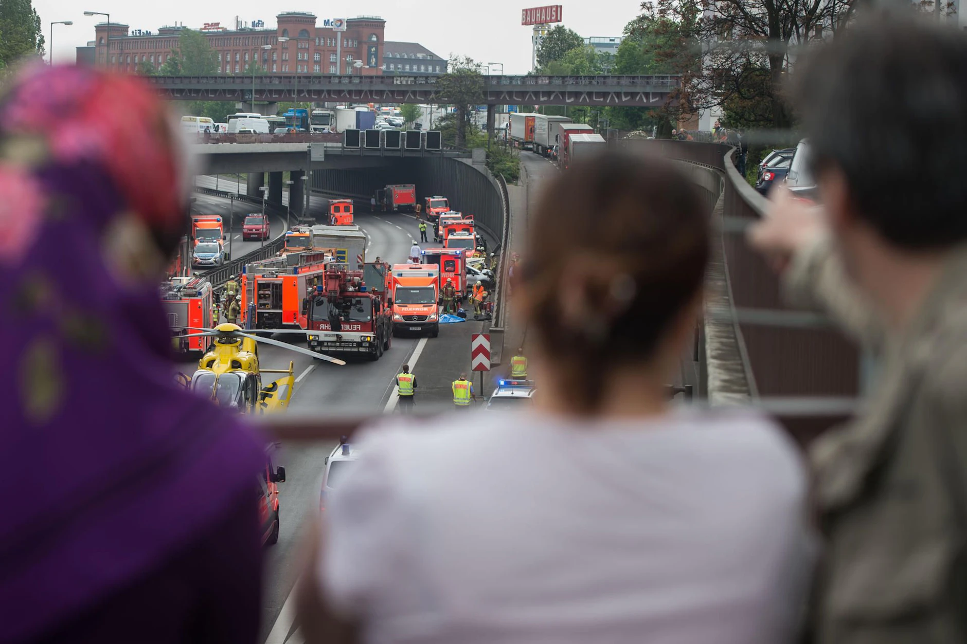 Schaulustige stehen auf dem Sachsendamm auf einer Brücke und beobachten einen Unfall. Sie heißen nicht mehr abwertend „Gaffer“, sondern, verständnisvoll: Zuschauende.
