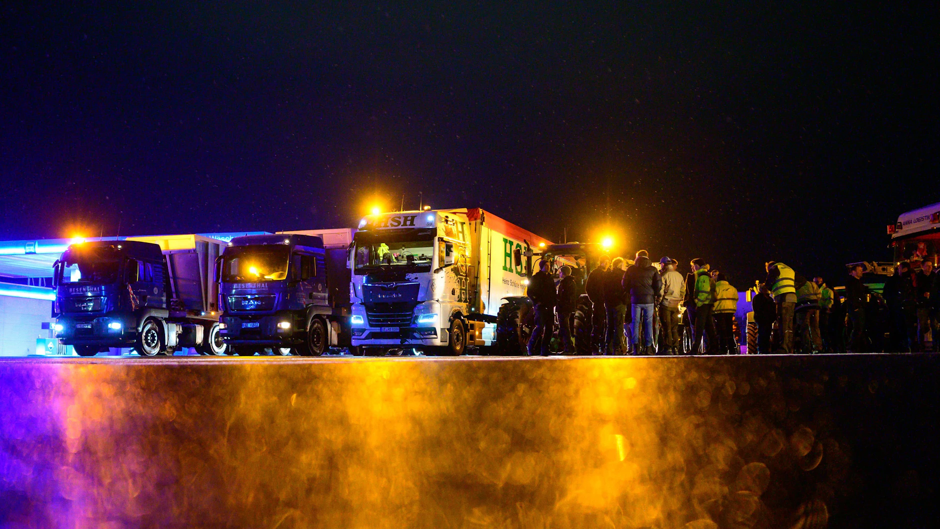 Landwirte stehen zusammen mit Lkw-Fahrern an einem Sammelplatz, kurz bevor sie zum Bauernprotest starten.