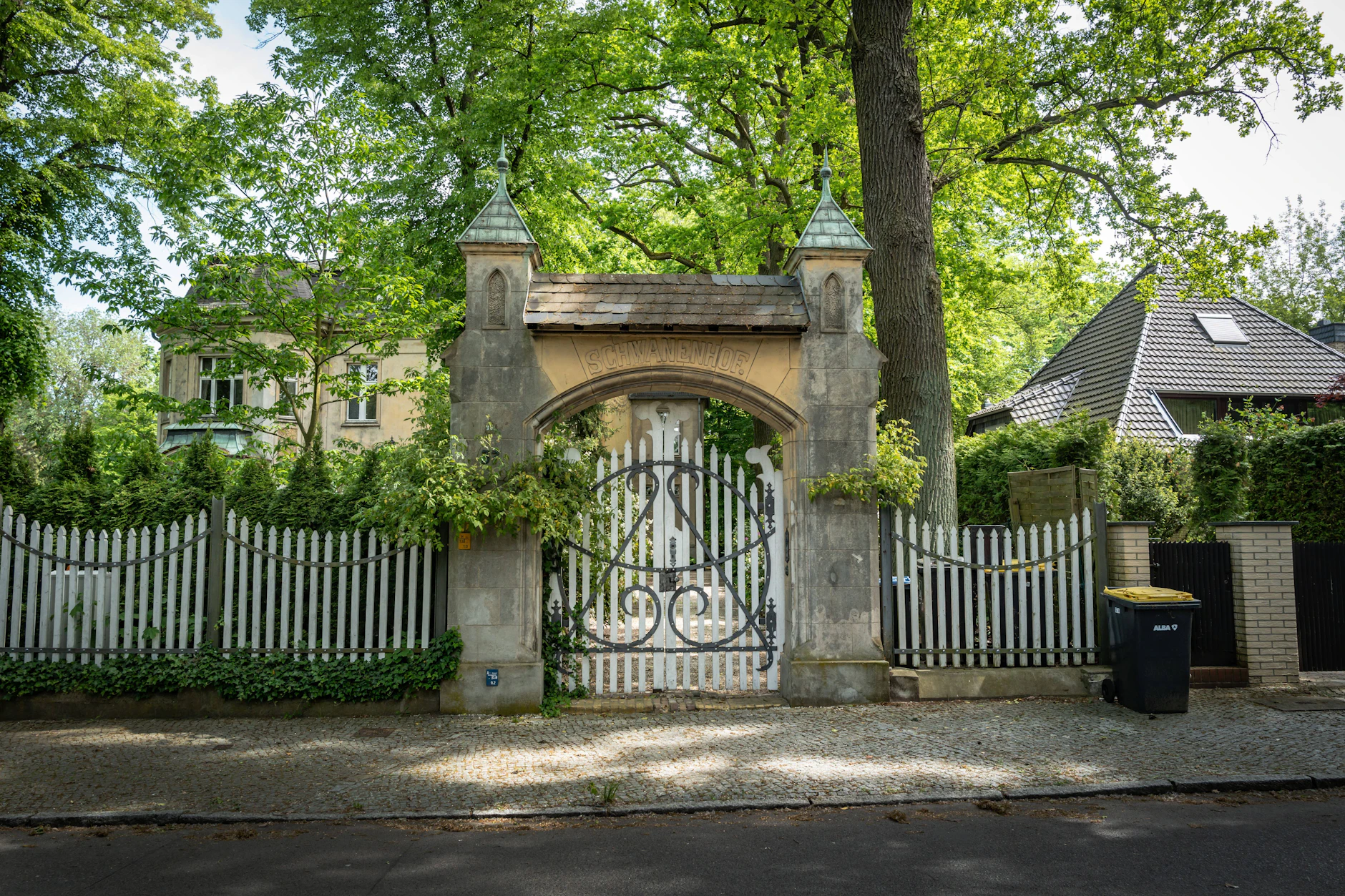 Von einem weißen, sanft geschwungenen Zaun umgeben: der Schwanenhof, von der Inselstraße aus gesehen