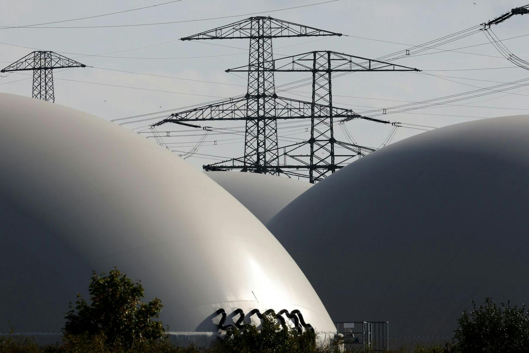 Hochspannungsmasten hinter den Speichern einer Biogasanlage: Wird die Industrie so in Zukunft mit einem Mix aus Erd- und Biogas versorgt?