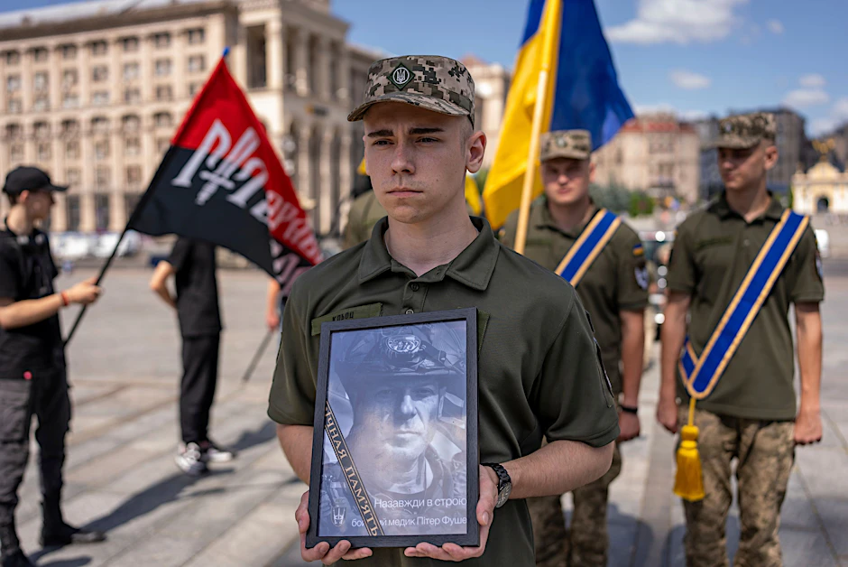 6. Juli 2024, Kiew: Ein ukrainischer Soldat trägt bei der Trauerfeier ein Porträt des britischen freiwilligen Sanitäters Peter Fouche, der am 27. Juni während seines Einsatzes in der Ostukraine getötet wurde.