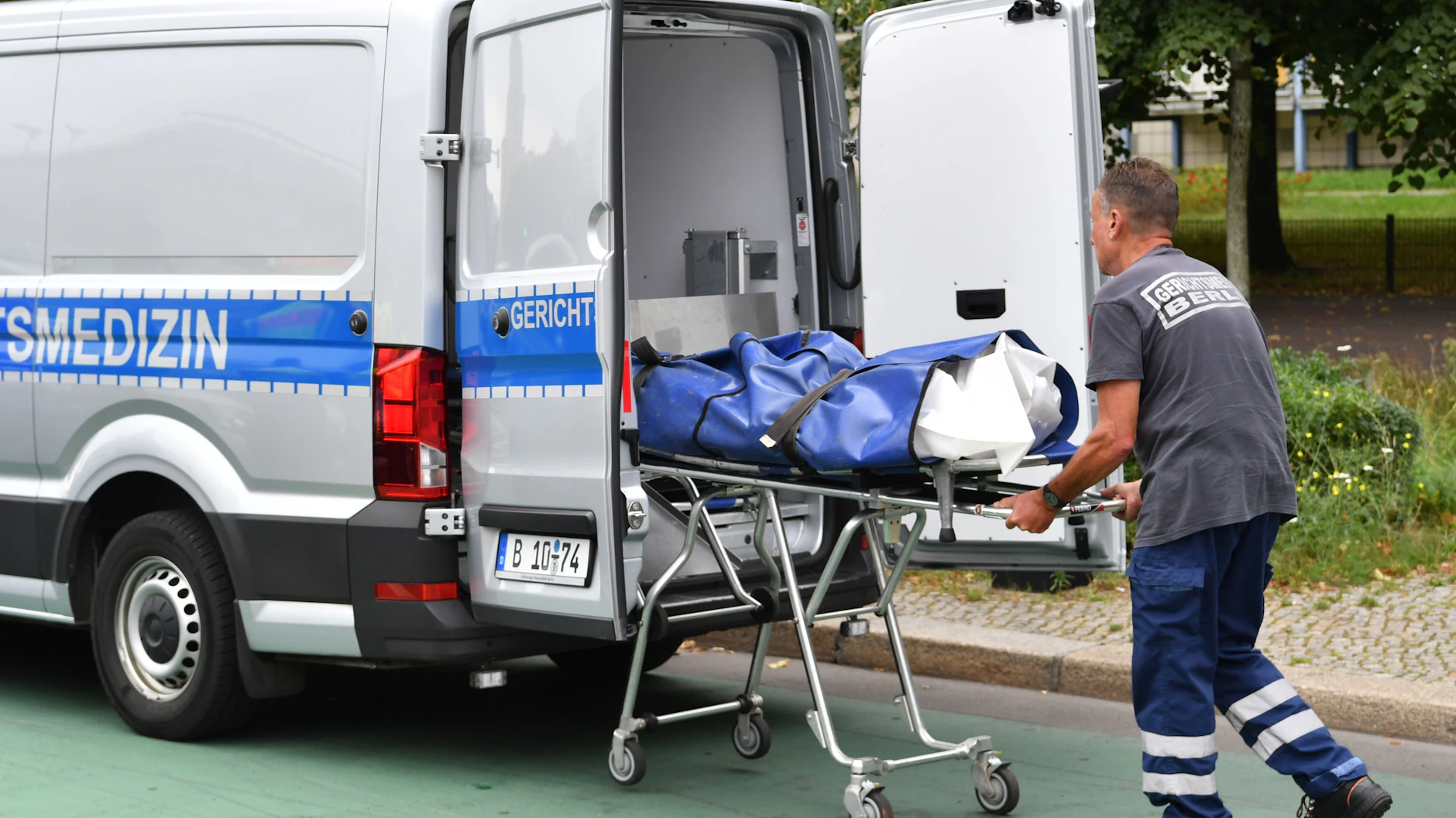 Ein Mitarbeiter der Gerichtsmedizin transportiert auf der Karl-Marx-Allee eine Leiche ab. Ein 41 Jahre alter Fußgänger ist am 18. August in Berlin-Mitte von einem Auto überfahren worden und ums Leben gekommen.