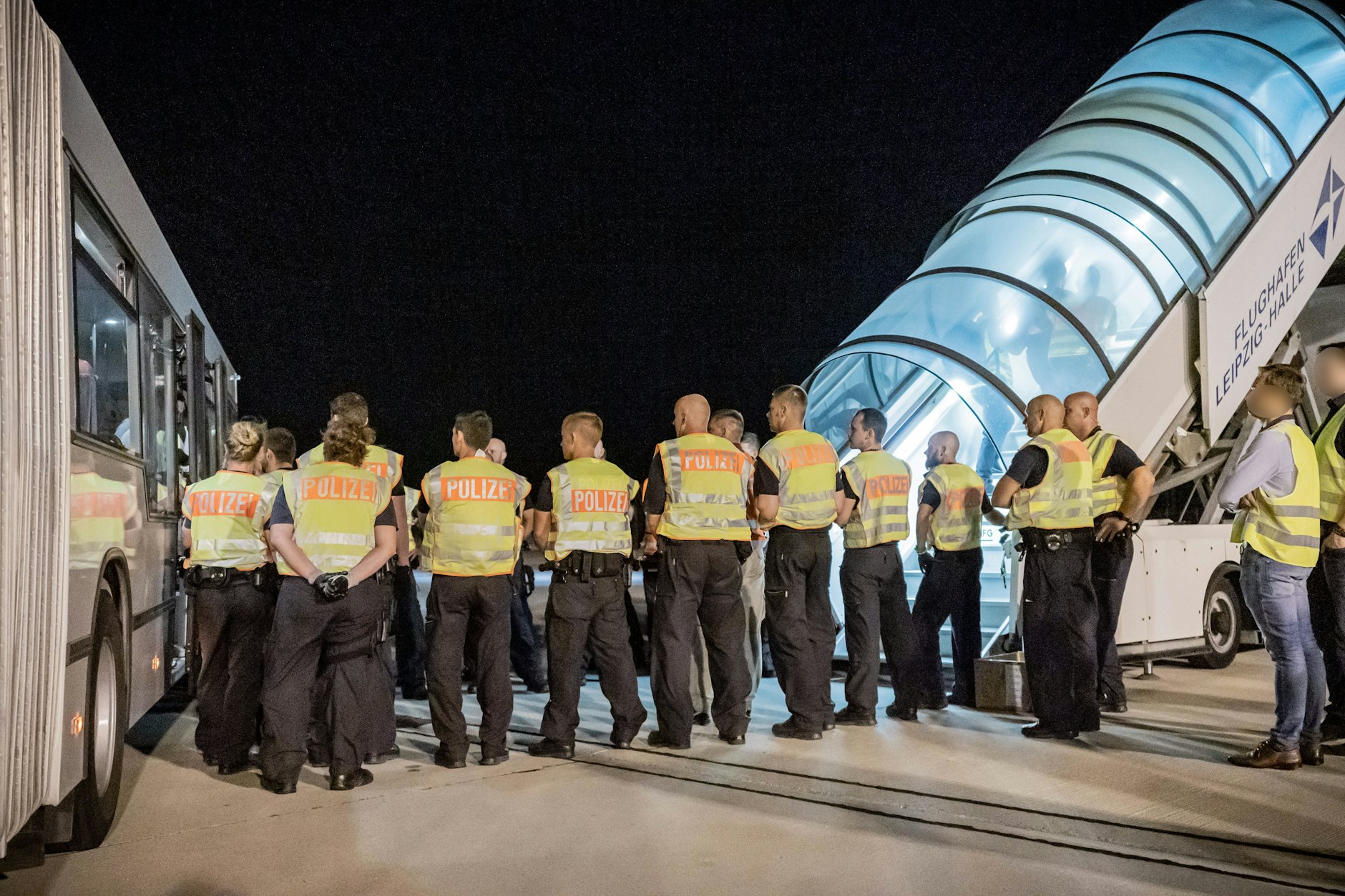 Polizeibeamte begleiten Afghanen auf dem Flughafen Leipzig-Halle in ein Charterflugzeug. 45 abgelehnte Asylbewerber wurden im Juli nach Kabul abgeschoben.