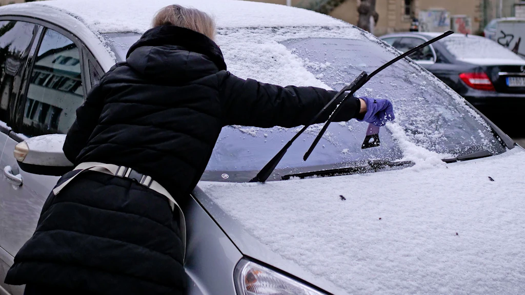 Der Winter hat Berlin erreicht: Eine Frau entfernt im Bezirk Steglitz-Zehlendorf mit einem Eiskratzer Schnee und Eis von der Frontscheibe ihres Autos. 