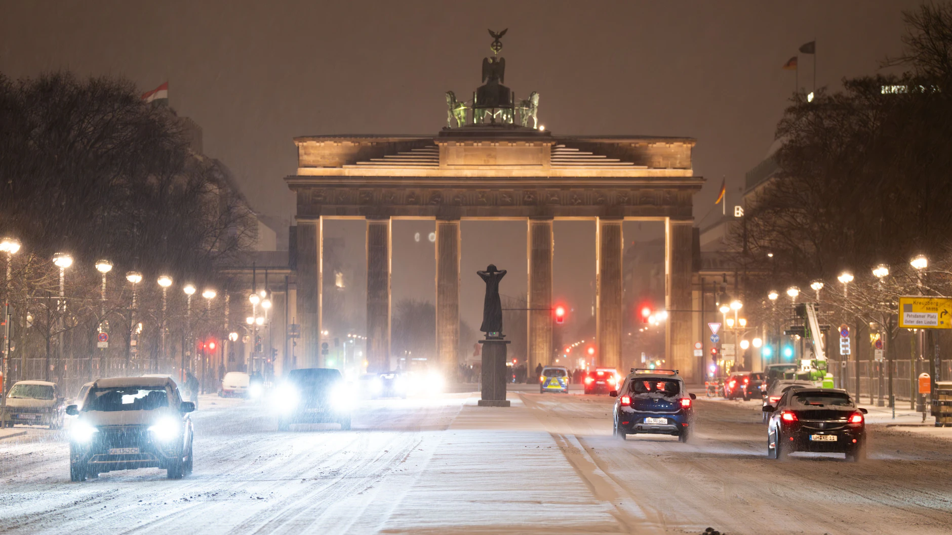 Autos fahren auf der zum Brandenburger Tor führenden, mit Schnee bedeckten Straße des 17. Juni.