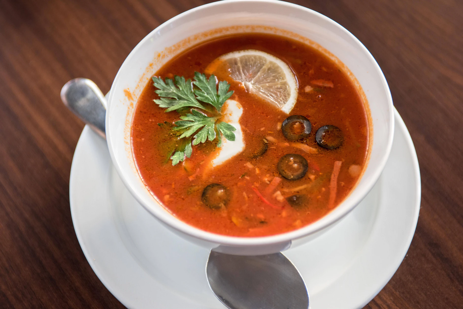 Eine traditionelle russische Soljanka: Zum Schluss kommen noch saure Sahne, Zitrone, Petersilie und Oliven dazu.