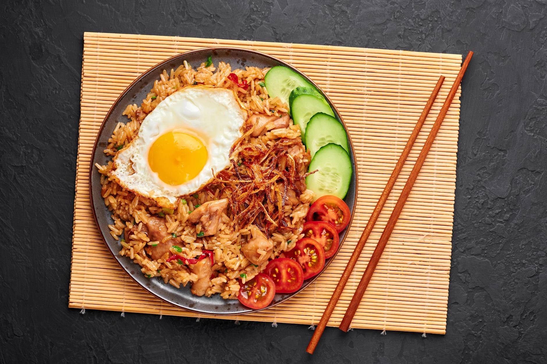 In Indonesien isst man Nasi Goreng meist mit Gabel und Reislöffel, es geht aber auch mit Stäbchen.