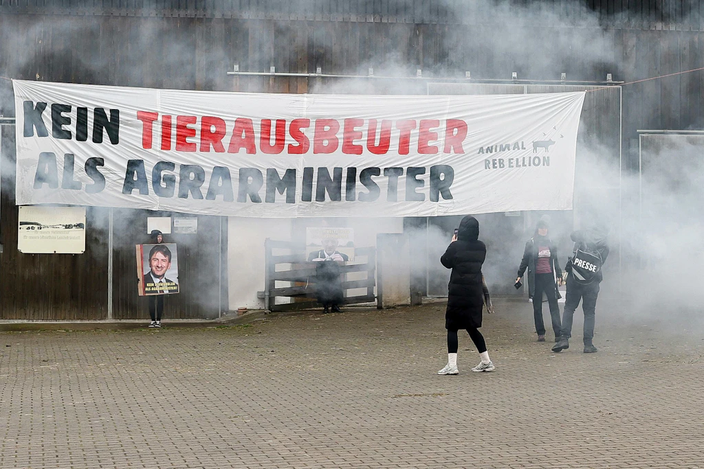 Mitglieder der Protestgruppierung Animal Rebellion halten Schilder mit Porträts vom Präsidenten des Bayerischen Bauernverbandes Felßner in die Höhe.