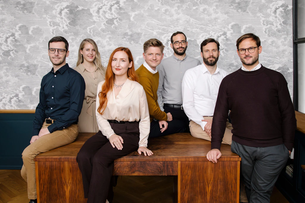 Hofers Kernteam, v. l.: Co-Gründer Franz-Josef Dröge, die Kunst- historikerinnen Deborah Kruck und Lea Döding, Gemmologe Florian Horsthemke, Fotograf Adam Blaufarb, Kunsthistoriker Malte Hesemann und Mastermind Simon Hofer. (Diese Tapete? „Nuvole“ von Cole and Son.)