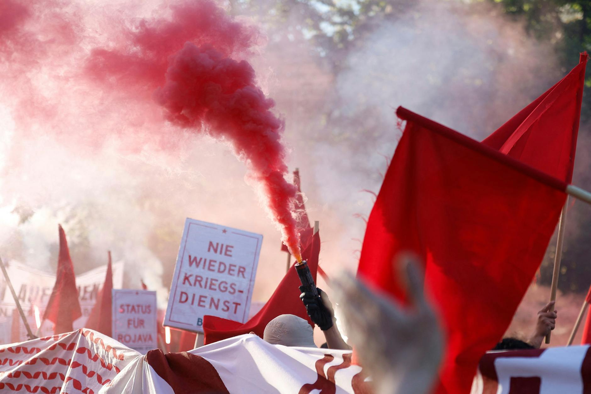Ein pro-palästinensischer Demonstrant hält eine rote Rauchfackel.