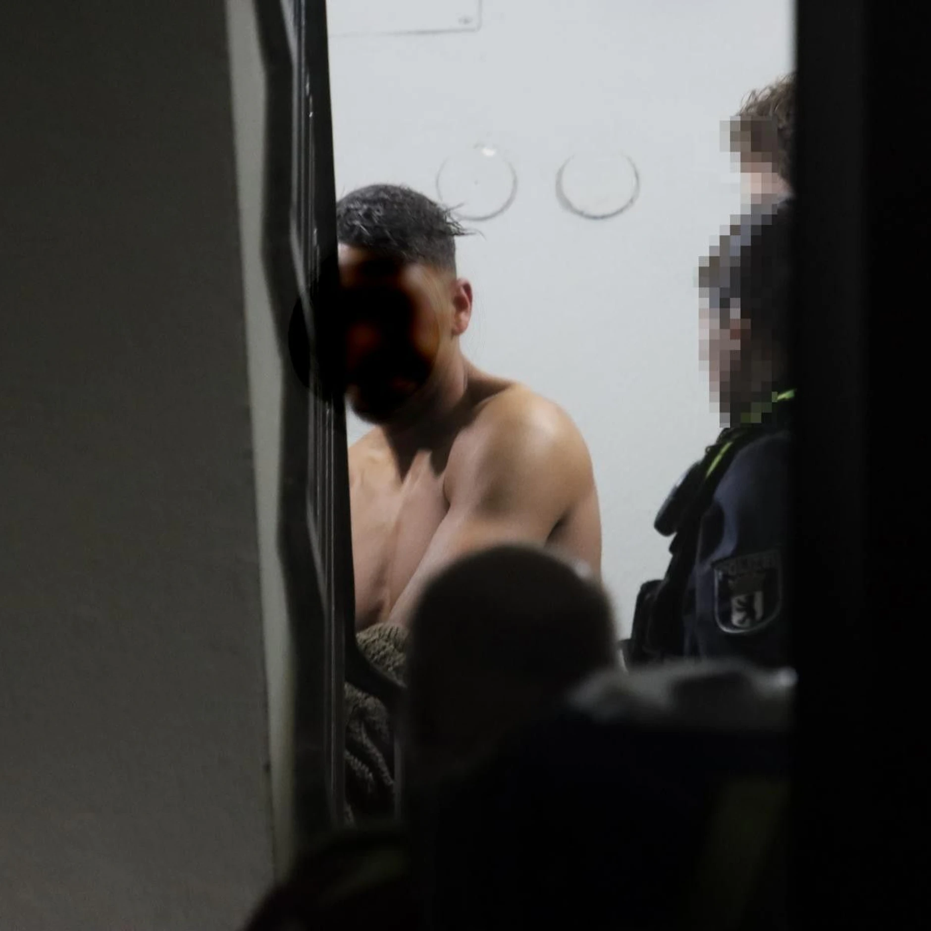 Im Treppenhaus muss der Mann sein Oberteil ausziehen: Die Rettungskräfte untersuchen ihn auf Verletzungen.