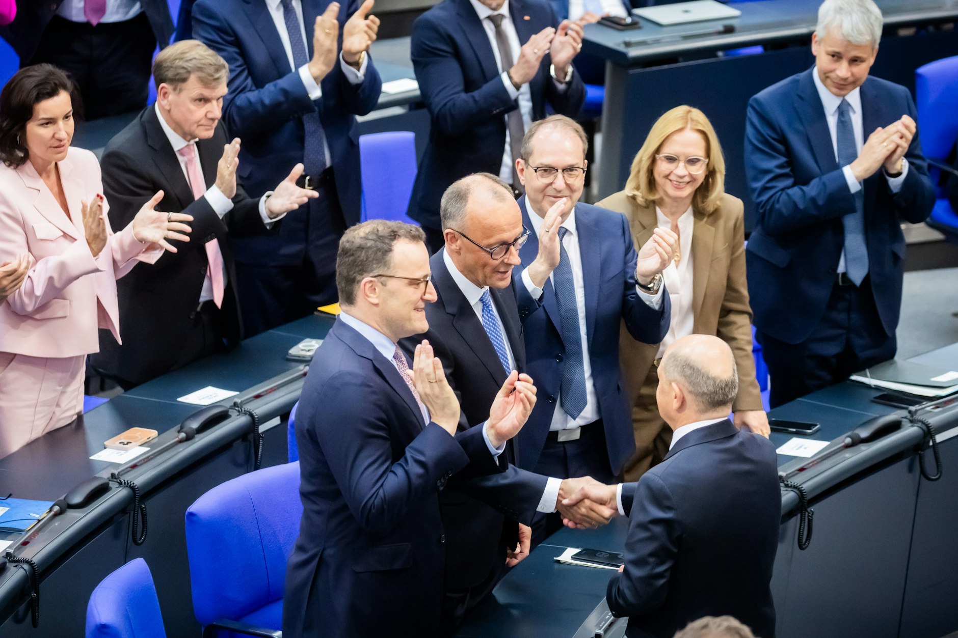 Der scheidende Bundeskanzler Olaf Scholz (unten, r, SPD) gratuliert dem neu gewählten Bundeskanzler Friedrich Merz (M, CDU) zu seiner Wahl im Bundestag.
