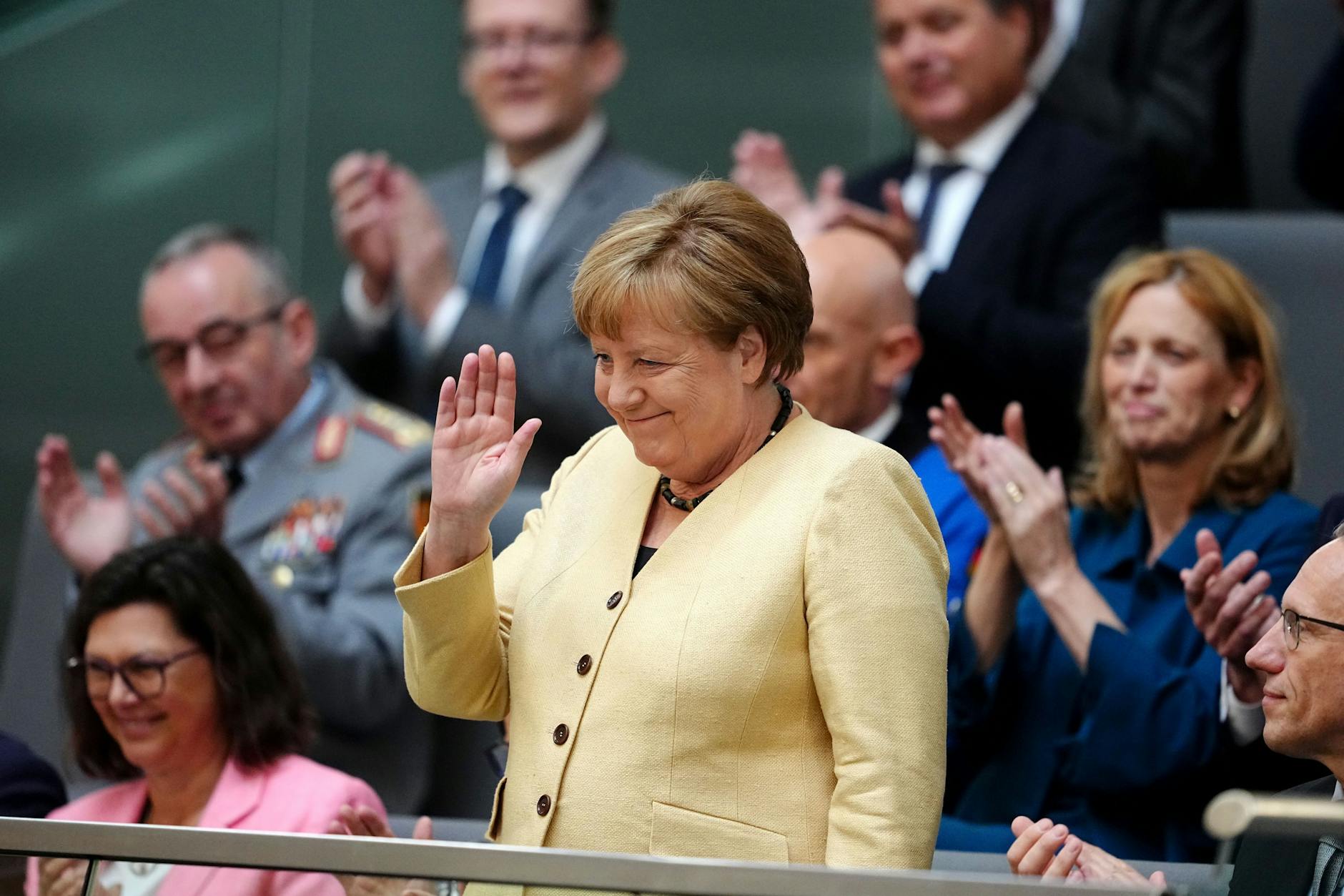 Angela Merkel (CDU), ehemalige Bundeskanzlerin, winkt vor der Kanzlerwahl im Bundestag auf der Tribüne.