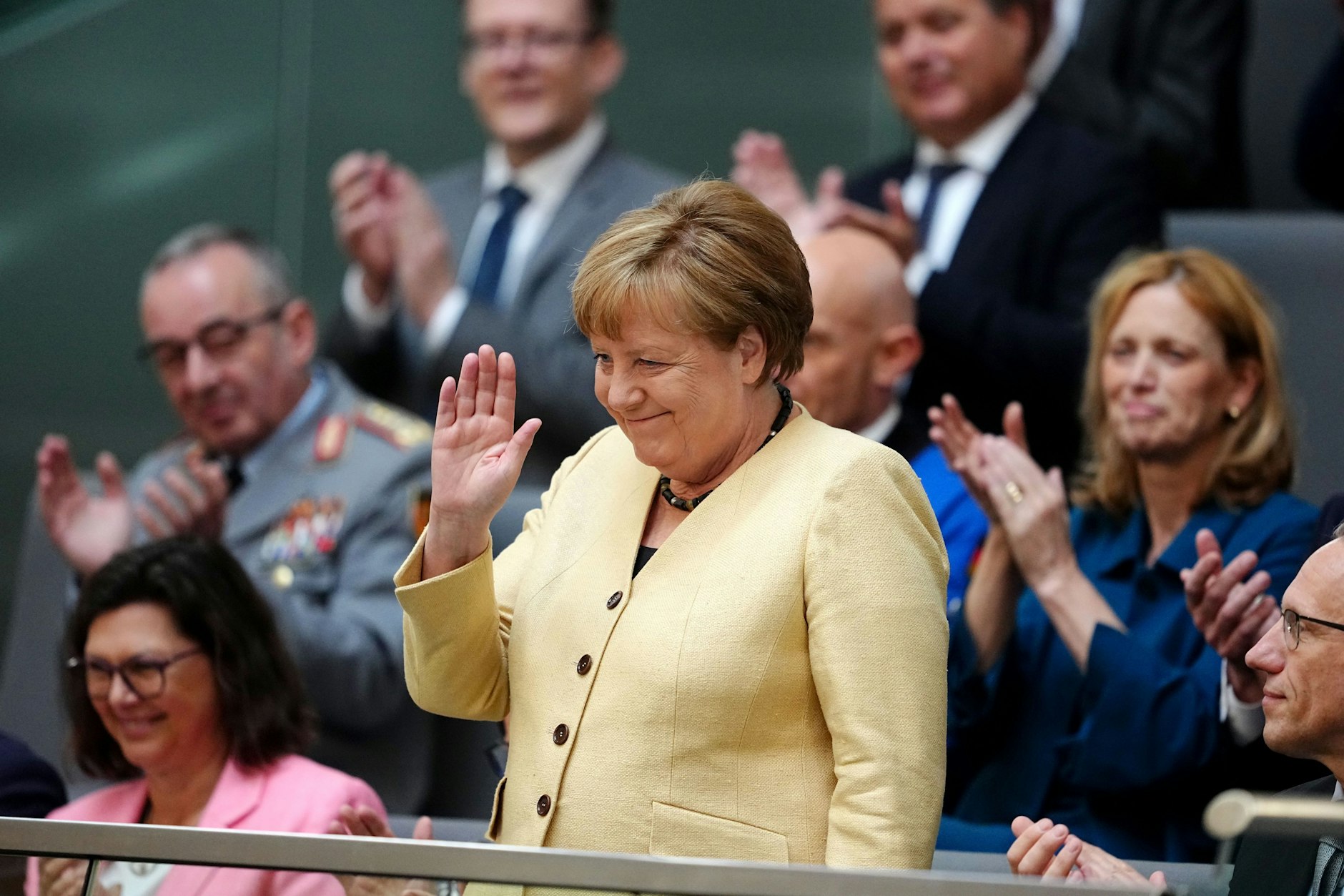 Angela Merkel (CDU), ehemalige Bundeskanzlerin, winkt vor der Kanzlerwahl im Bundestag auf der Tribüne.