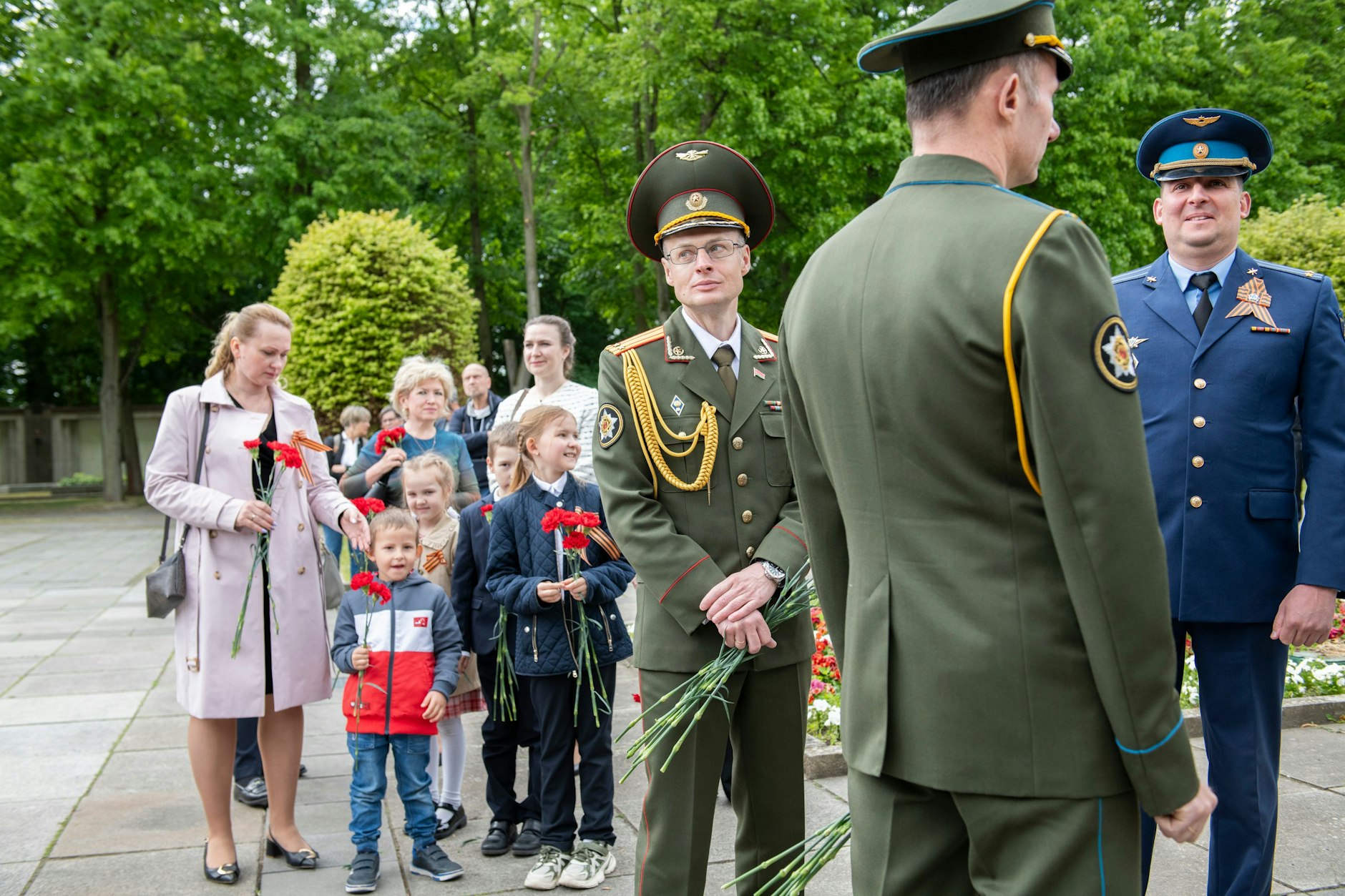 Kinder legen am Sowjetischen Ehrenmal in der Schönzholzer Heide Blumen ab.