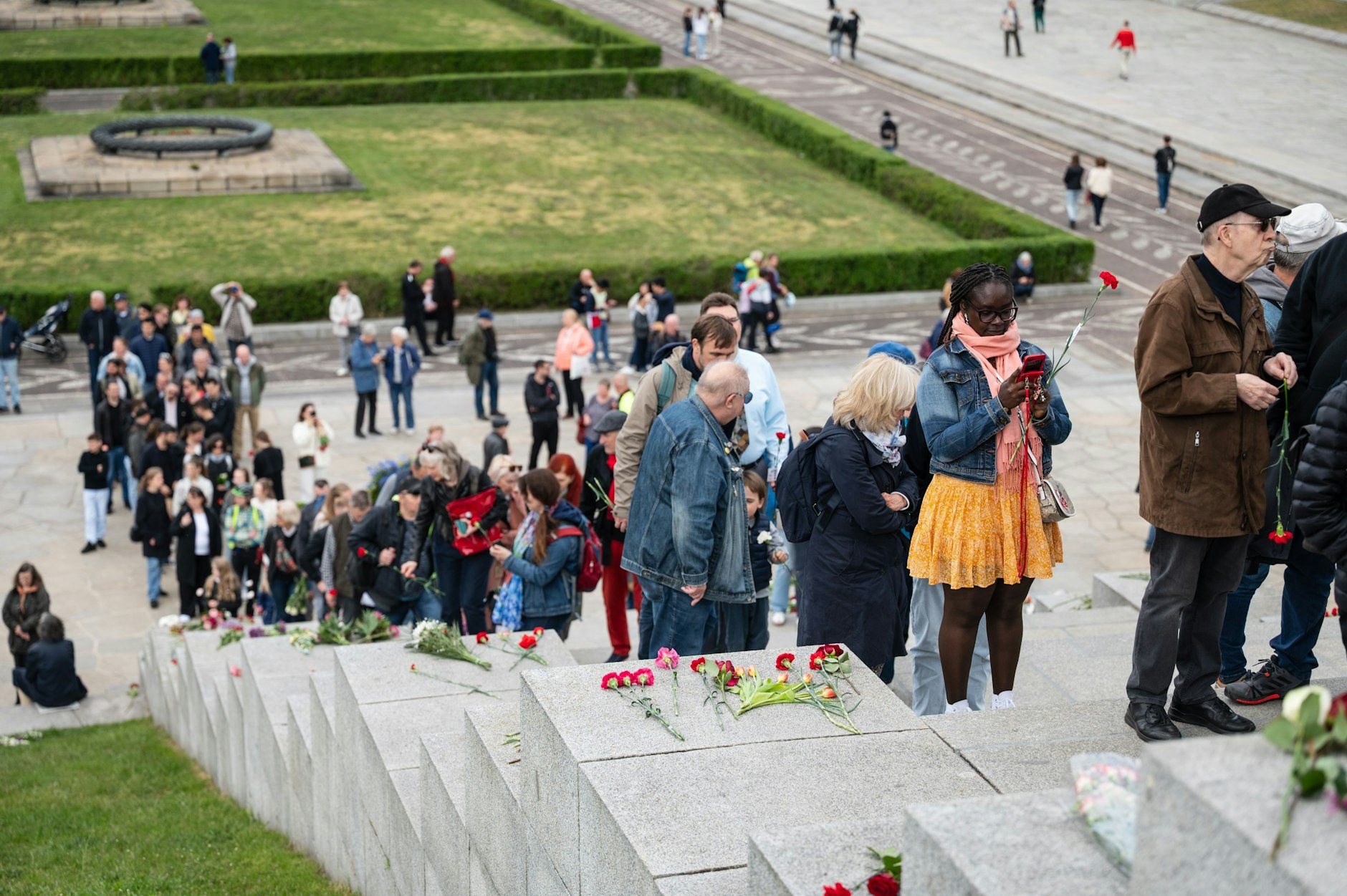 Menschen laufen das Ehrenmal im Treptower Park hoch.