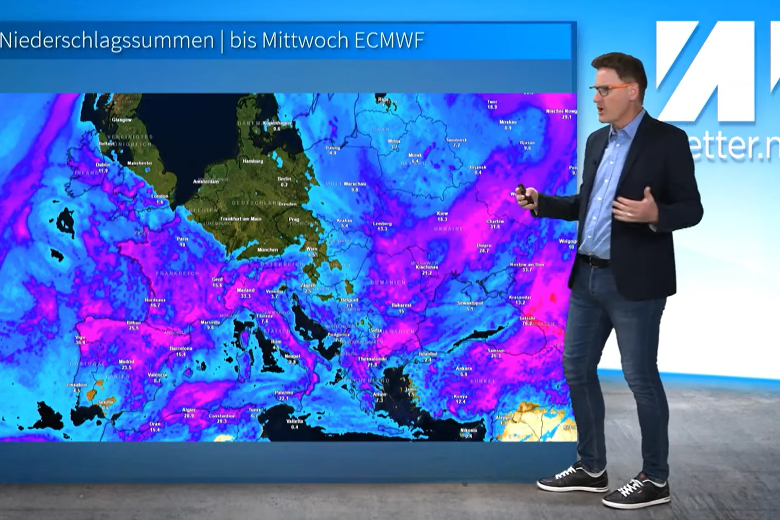 Meteorologe Dominik Jung von wetter.net steht vor der Niederschlagswetterkarte, die für Deutschland, die Benelux-Länder, die britischen Inseln und Teile Tschechiens null Regen verspricht. Ringsherum (blau) kann es schon mal ab und zu regnen.