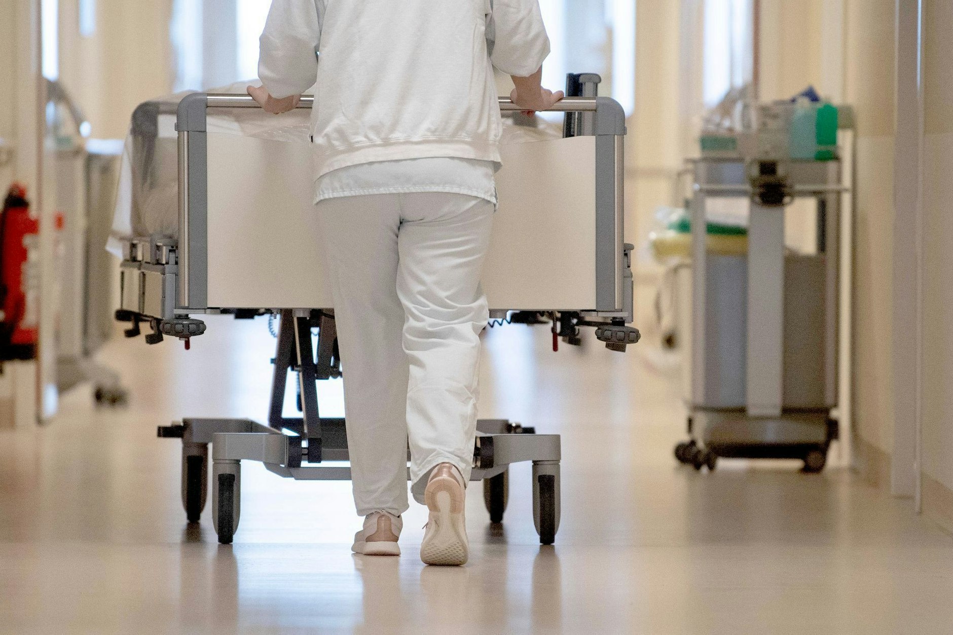 Eine Pflegekraft schiebt ein Bett über den Flur eines Krankenhauses.