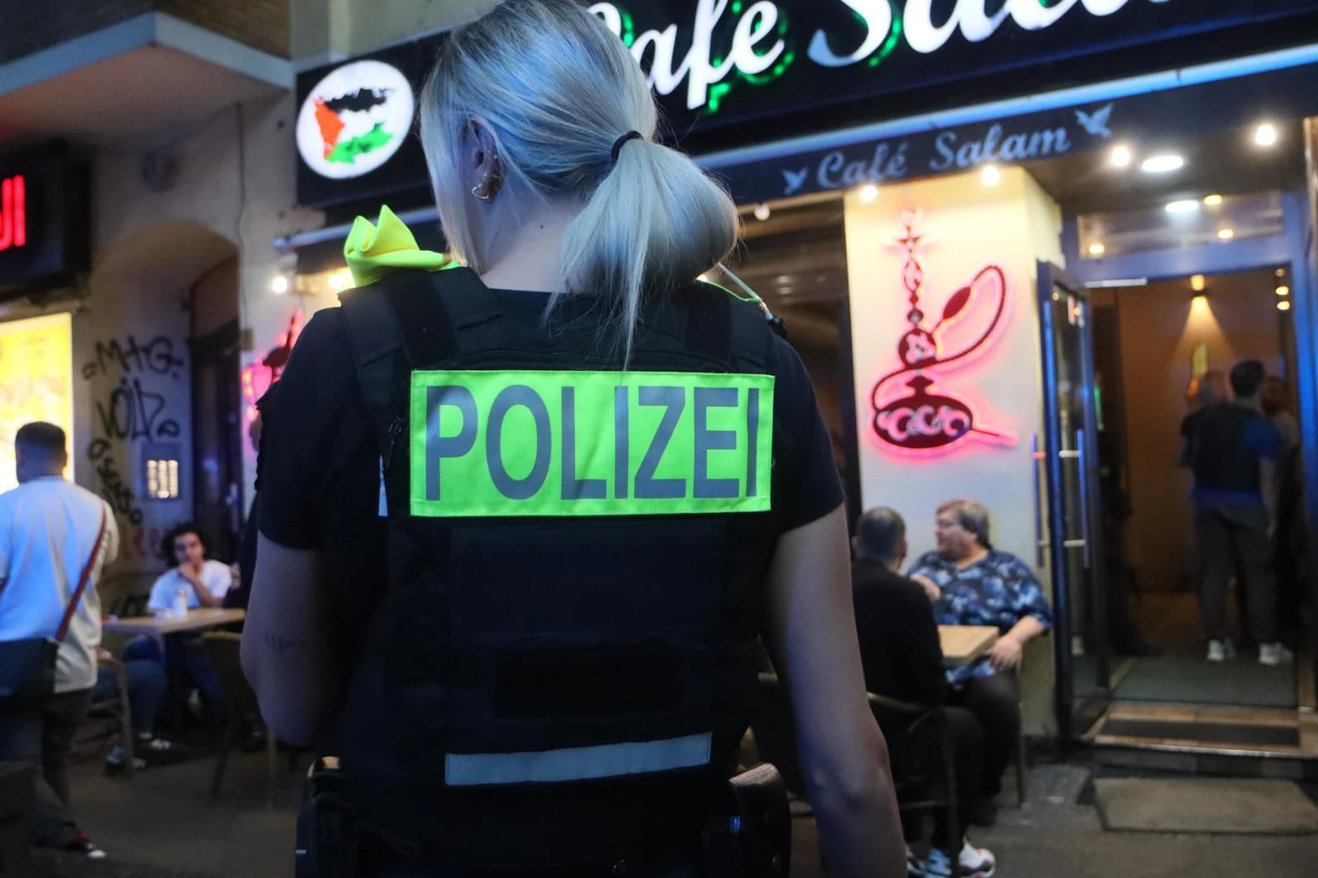 Eine Polizeibeamtin sichert 2025 bei einer Großrazzia in Neukölln gegen Clans einen Lokaleingang ab.