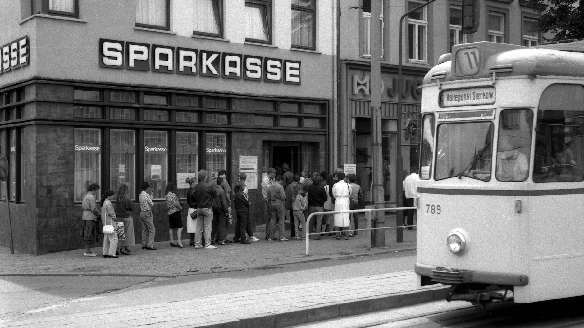 Menschen stehen an einer Sparkasse in Rostock Schlange - sie wollen zum ersten Mal D-Mark abheben. Die Deutsche Mark verbanden zur Währungsunion viele mit besonderen Wünschen und Träumen.