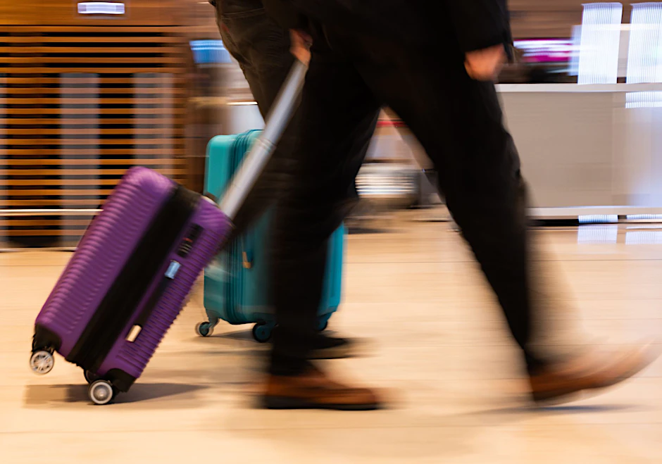 Menschen gehen im Terminal 1 am Flughafen Berlin Brandenburg mit Gepäck durch die Haupthalle.