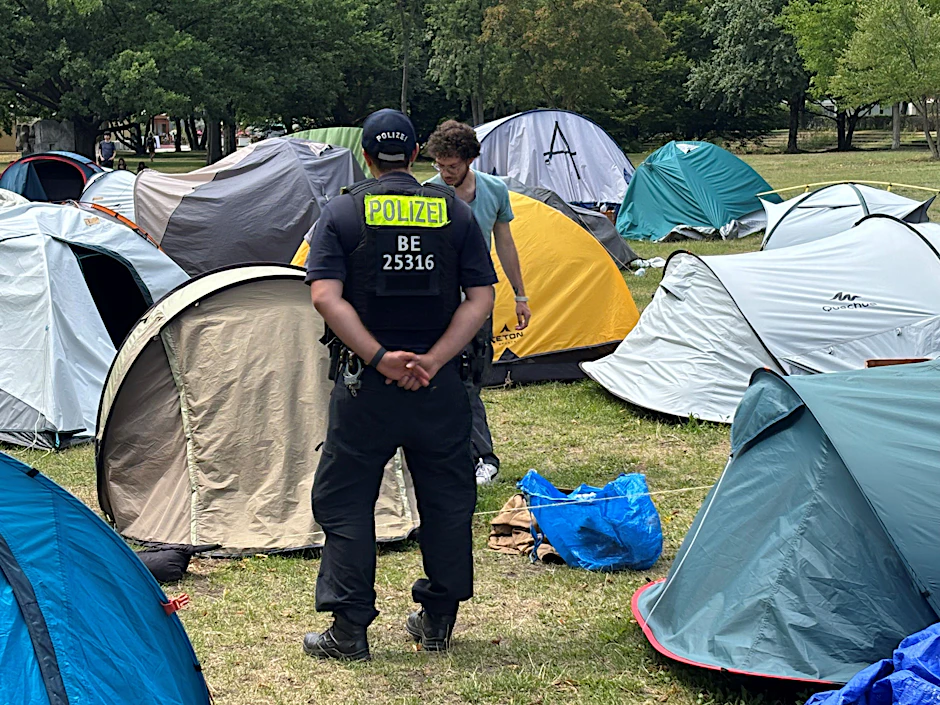 Ein Polizist passt auf, wie ein Bewohner des Protestcamps seine Sachen zusammenräumt.