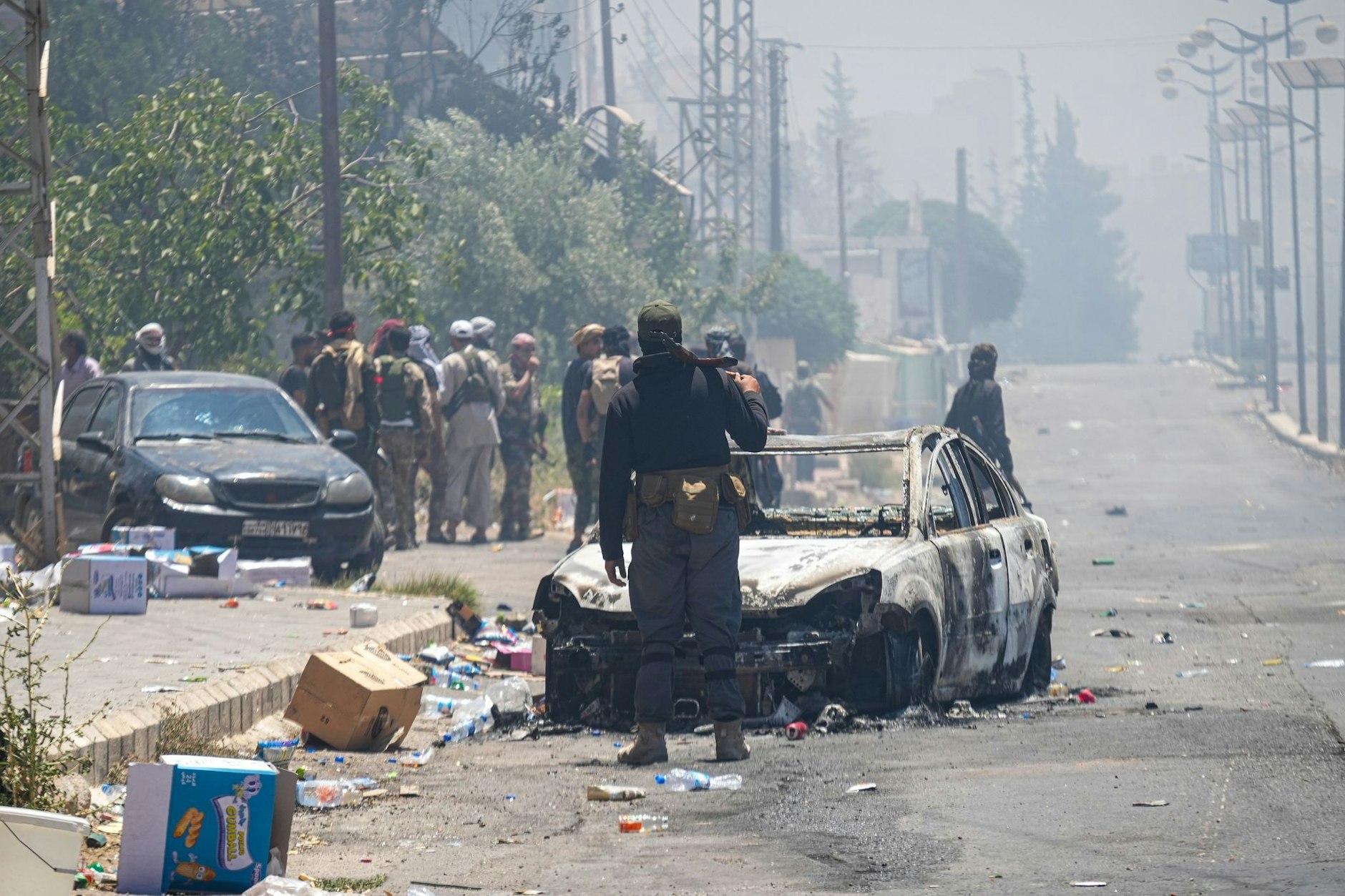 Beduinen und Stammeskämpfer versammeln sich in der Stadt As-Suwayda, während Rauch von brennenden Häusern inmitten von Zusammenstößen zwischen Stammeskämpfern und lokalen drusischen Gruppierungen im Süden Syriens aufsteigt.