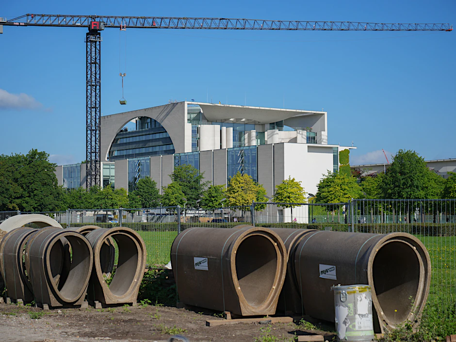 Baumaterial liegt auf der Wiese vor dem Reichstag vor der Kulisse des Kanzleramtes. Der Bau soll erweitert werden. Die Kosten sind immens.