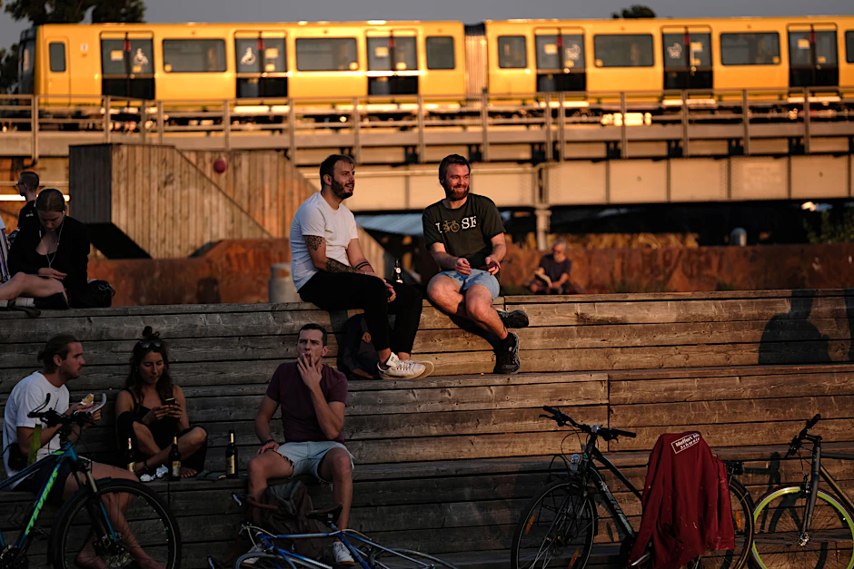 <em>Summer in the City</em>: An einem heißen Tag gibt es im Biergarten am Gleisdreieck Abkühlung. Die Fahrgäste der U-Bahn, die den Park auf Brücken überquert, müssen in der Hitze ausharren.