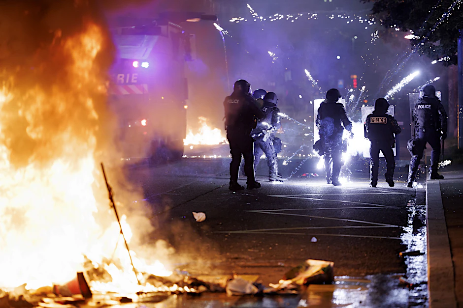 Schweiz, Lausanne: Polizei steht an einer brennenden Barrikade an der Avenue de Morges (Stadtteil Prelaz) bei Ausschreitungen in der zweiten Nacht nach dem tödlichen Unfall eines jungen Mannes.