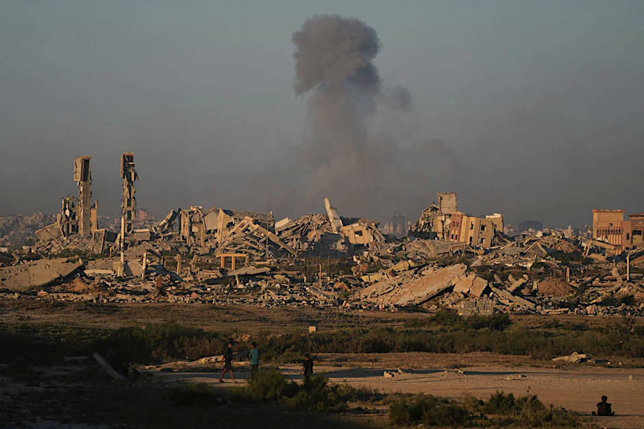 Rauch steigt hinter den Überresten zerstörter Häuser nach einem Bombardement der israelischen Armee in der Stadt Gaza auf.