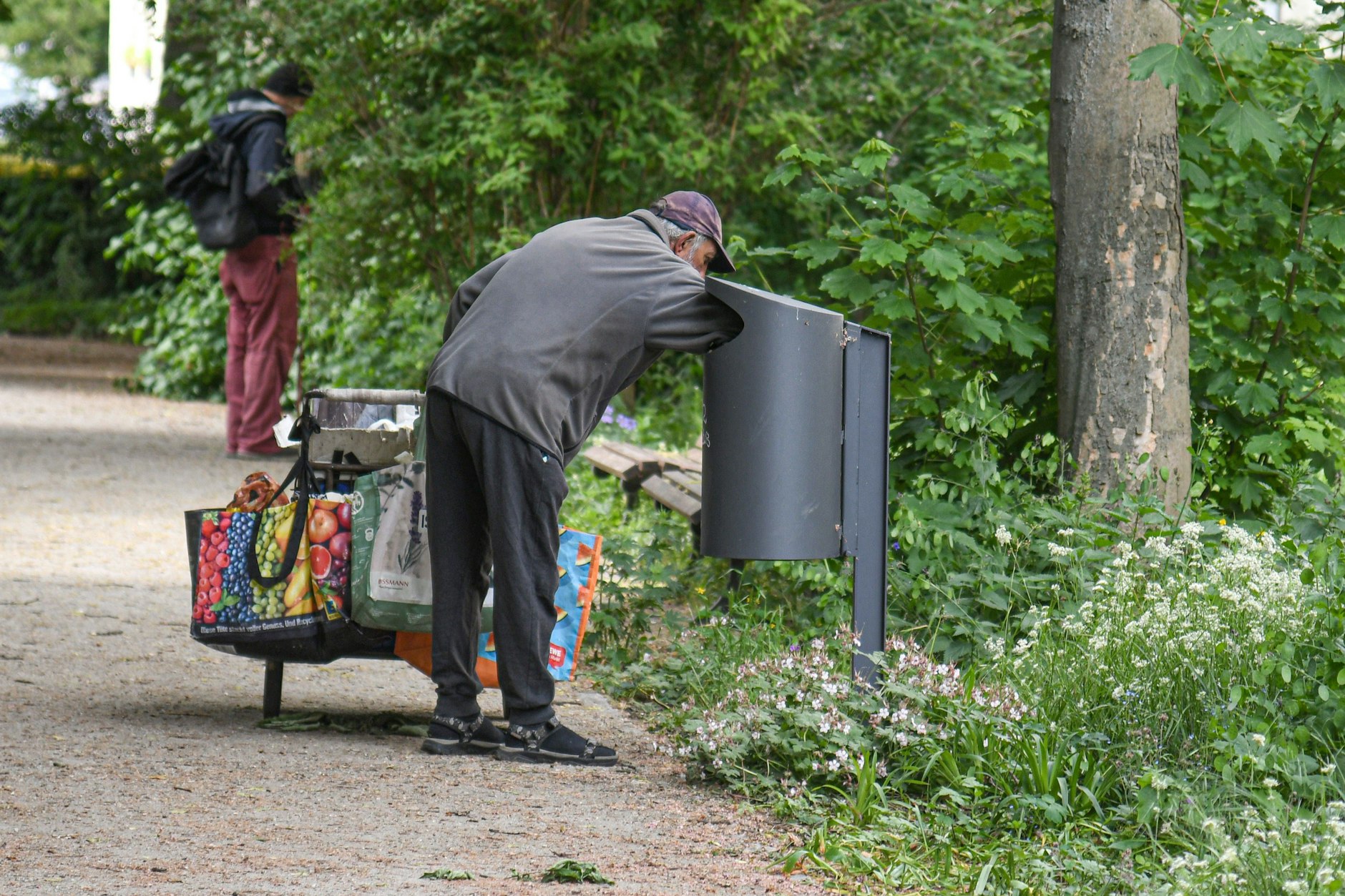 Ein älterer Mann durchsucht einen Abfalleimer nach leeren Flaschen.