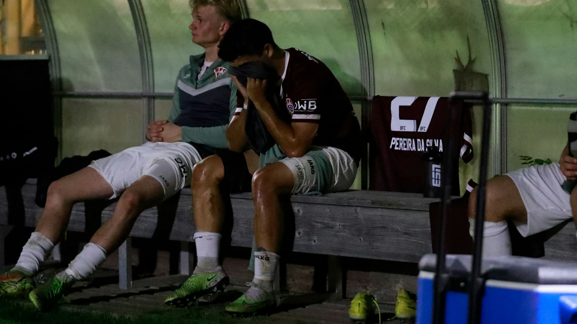 Jan Shcherbakovski sitzt nach seinem Kurzeinsatz bei Chemie Leipzig verzweifelt auf der Bank: Trikot vorm Gesicht, Eisbandage am rechten Oberschenkel.