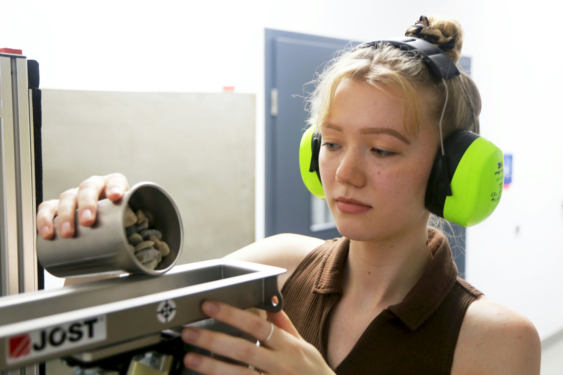 Vorbereitung einer Steinschlagprüfung: Tessa-Katharina Hoyer füllt Beschussmaterial in das Gerät des Aucoteam-Teststands.
