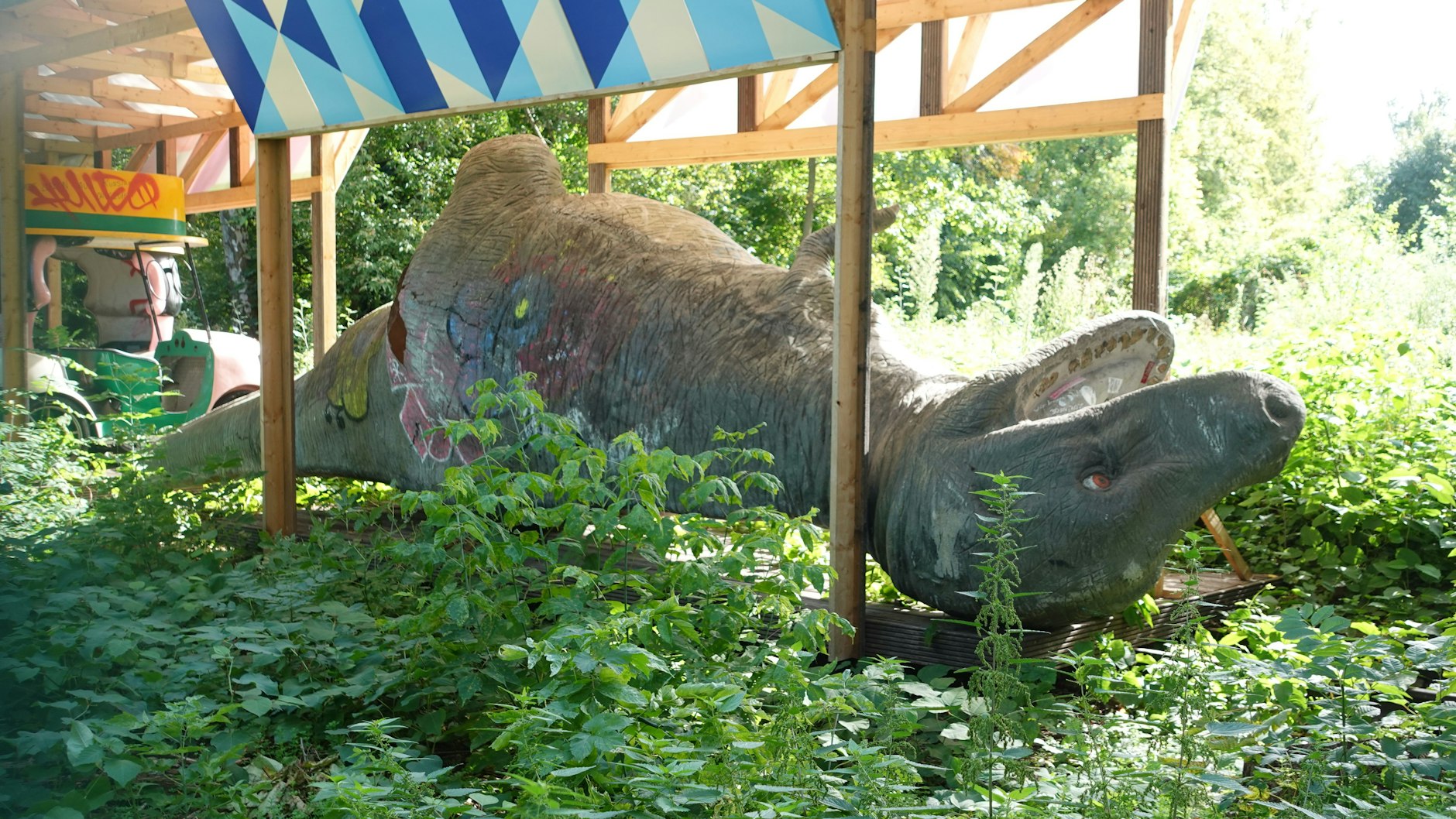 Ein T-Rex und Teile von Fahrgeschäften: Gleich hinter dem Zaun am Spree-Uferweg lagern die Hinterlassenschaften des alten Spreeparks.