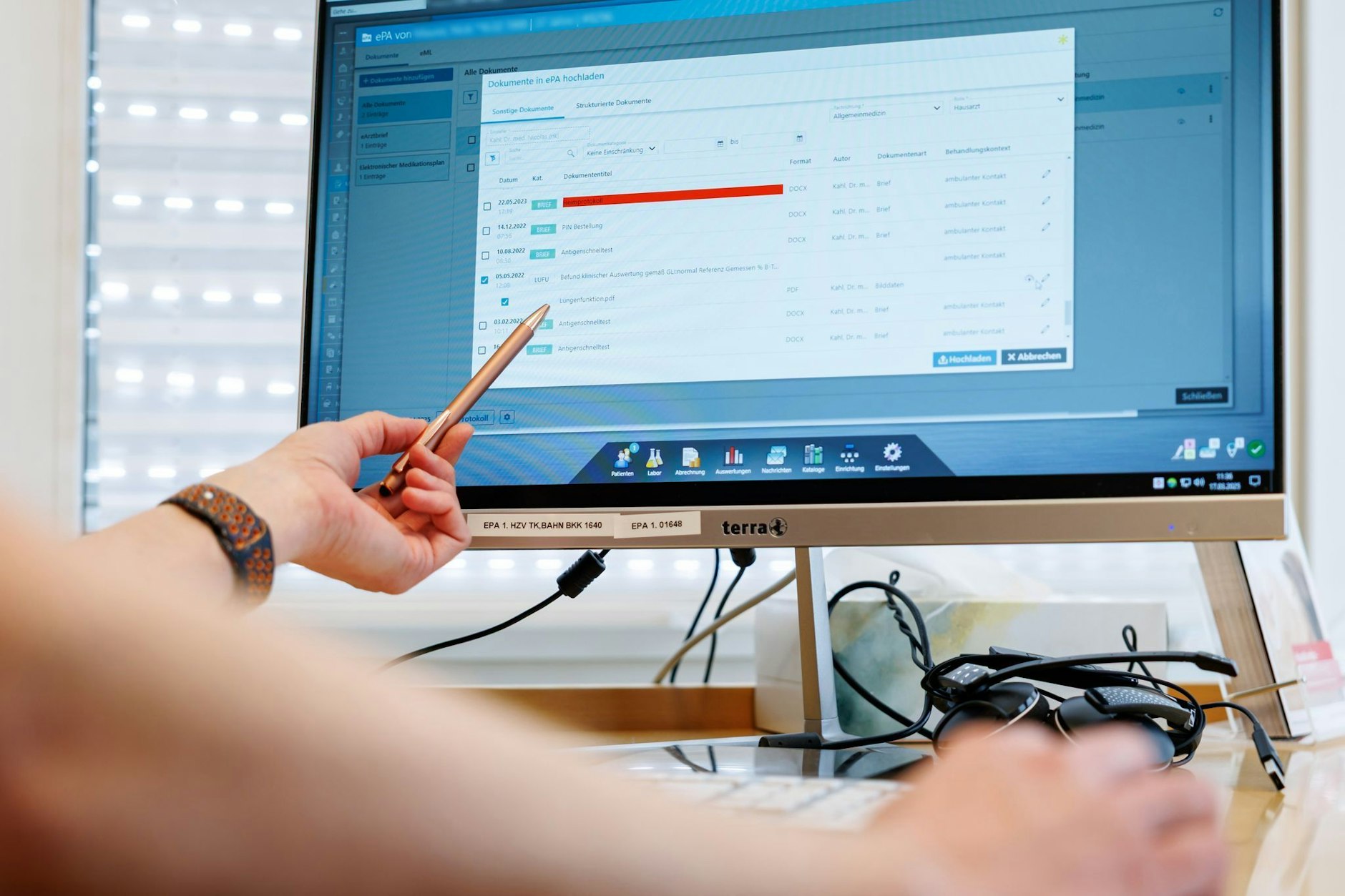 Ein Hausarzt lädt in seiner Praxis Dokumente in eine elektronische Patientenakte hoch.