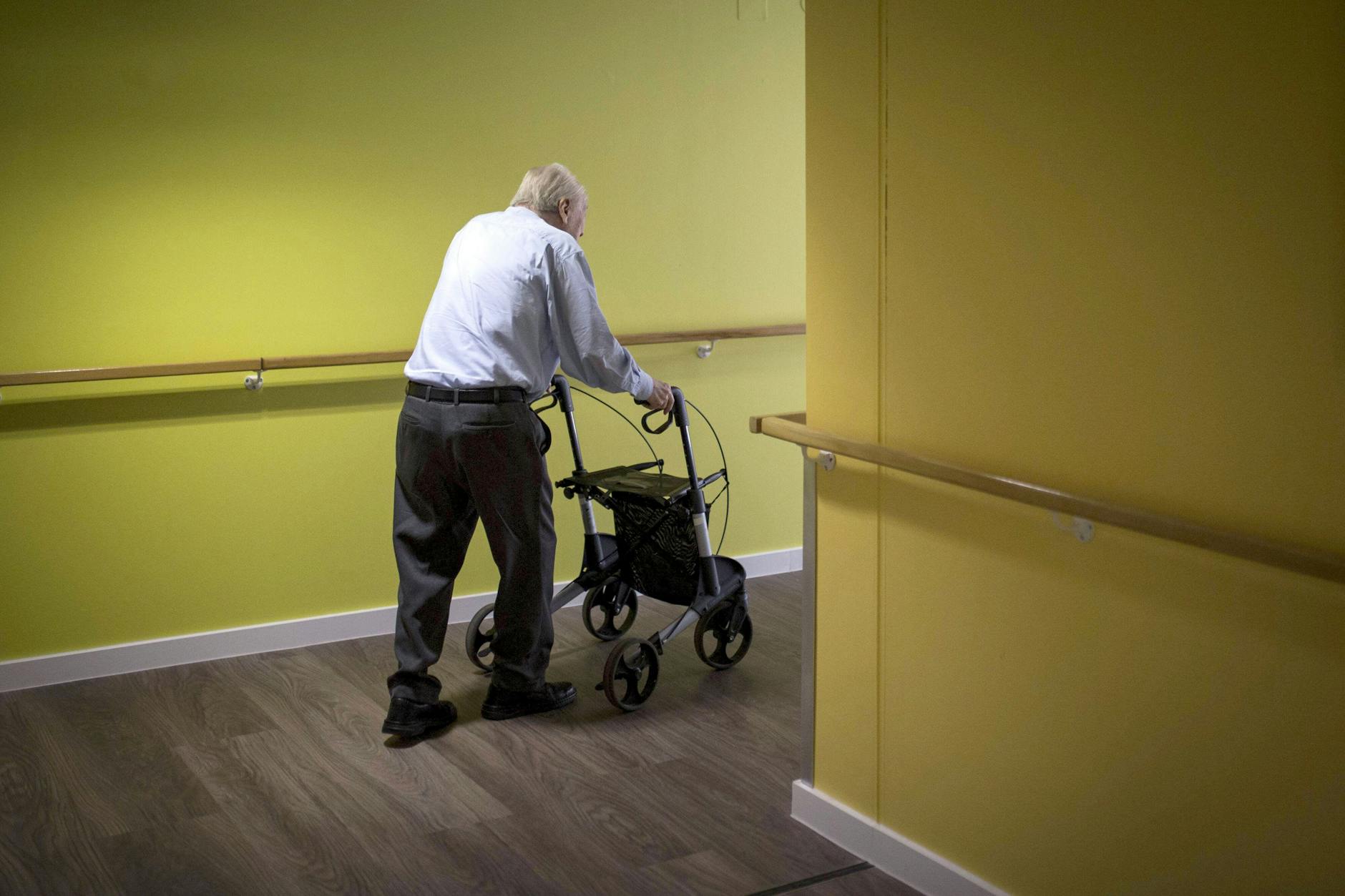 Ein Mann geht am Rollator über den Flur eines Pflegeheims.