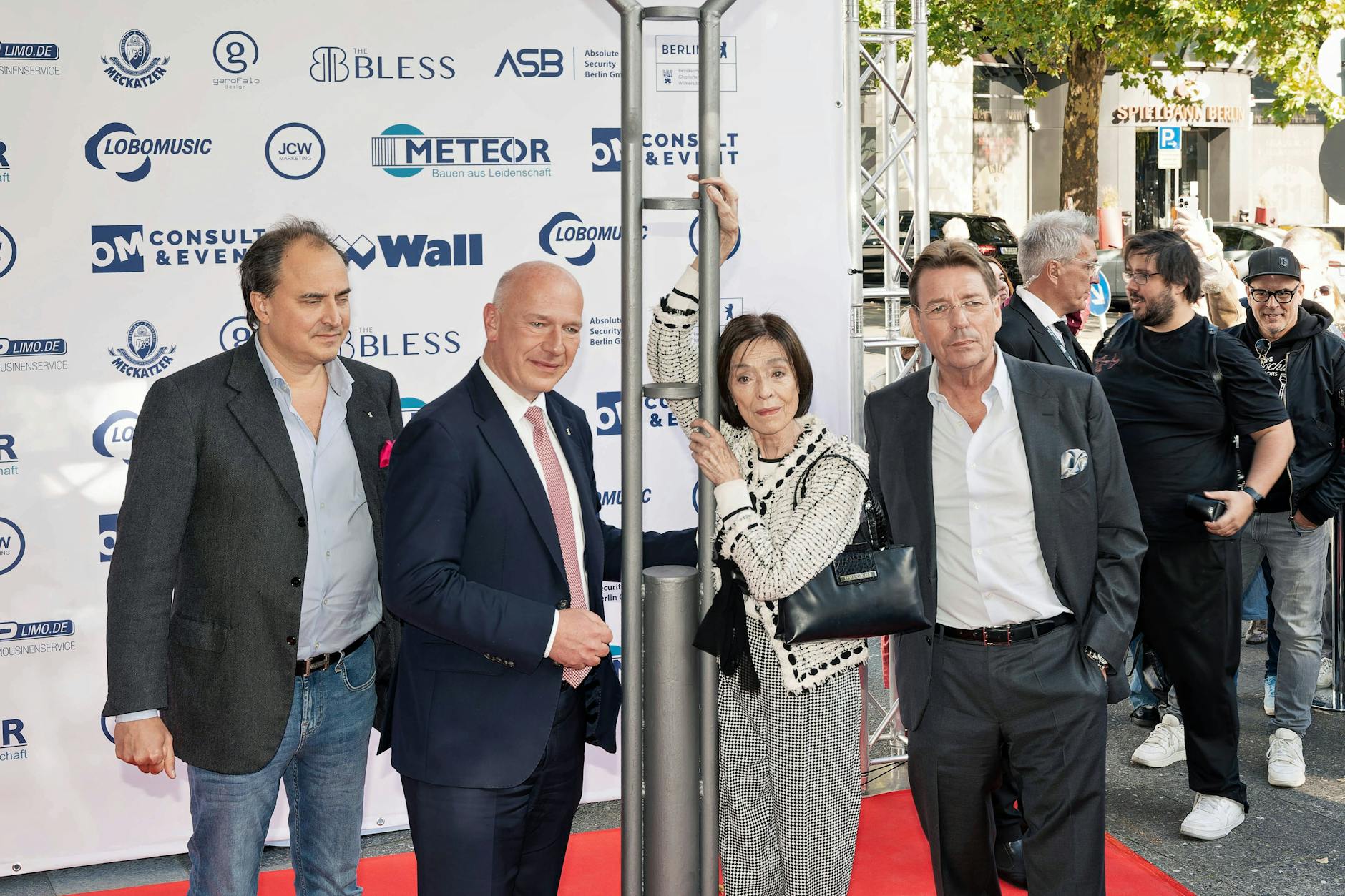 Festlich eingeweiht: Vor dem Schild am Harald-Juhnke-Platz in Berlin stehen Juhnkes Sohn Oliver, der Regierende Kai Wegner, Susanne Juhnke und Juhnkes Ex-Manager Peter Wolf.