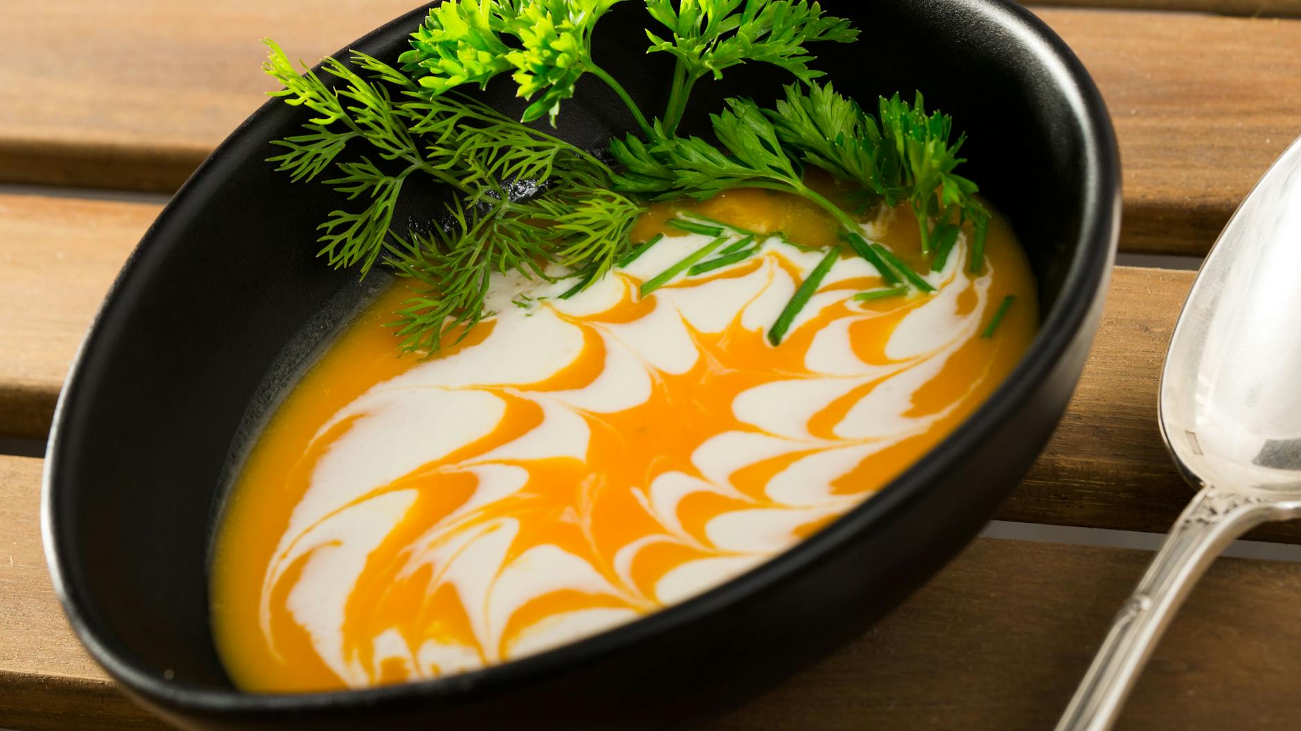 Mit Crème fraîche kann man ein hübsches Topping auf die Kürbissuppe zaubern.