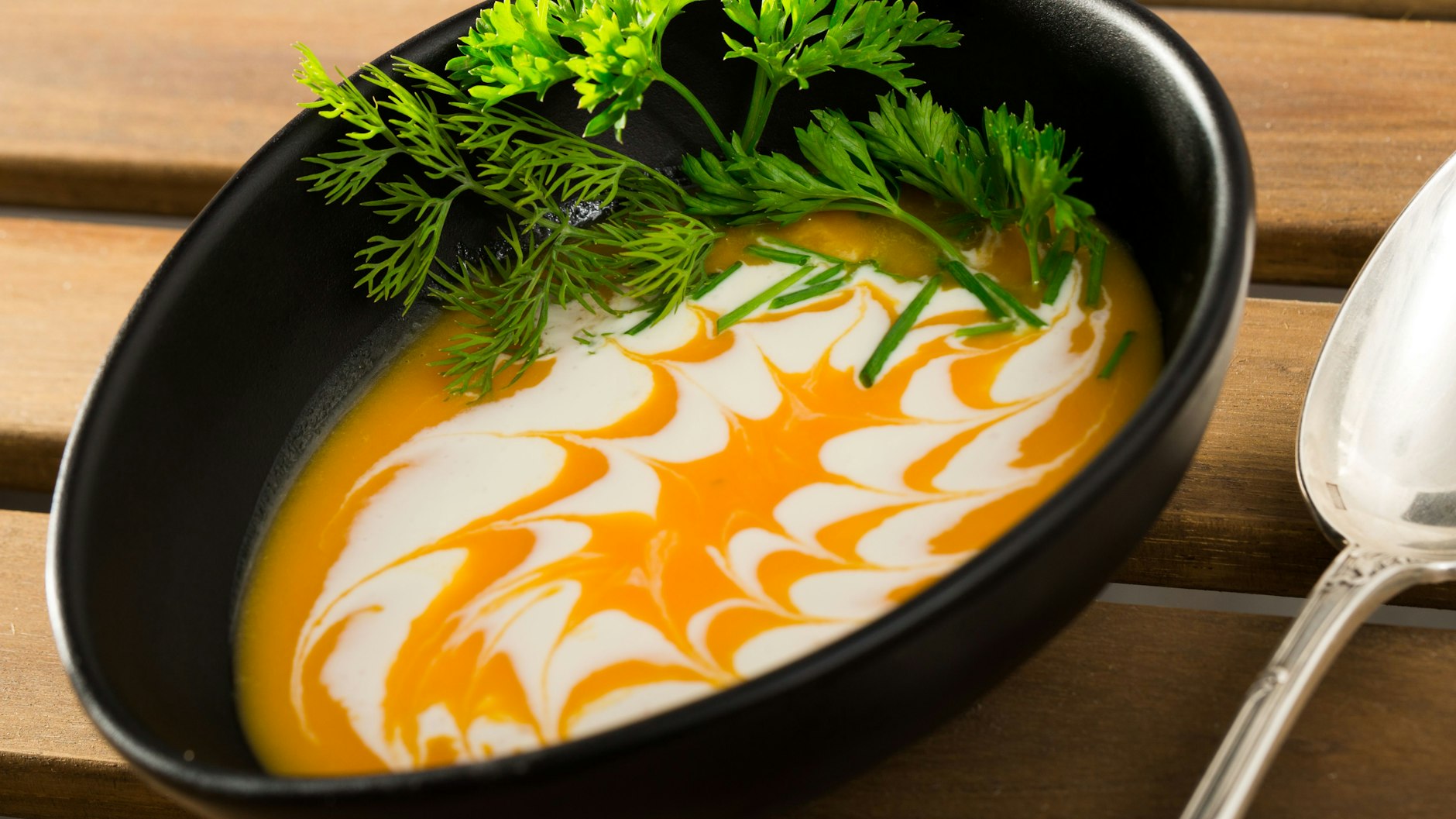 Mit Crème fraîche kann man ein hübsches Topping auf die Kürbissuppe zaubern.