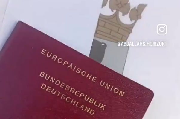 Stolz zeigt der Neu-Staatsbürger seinen deutschen Pass. Im Hintergrund das Berliner Wappen.