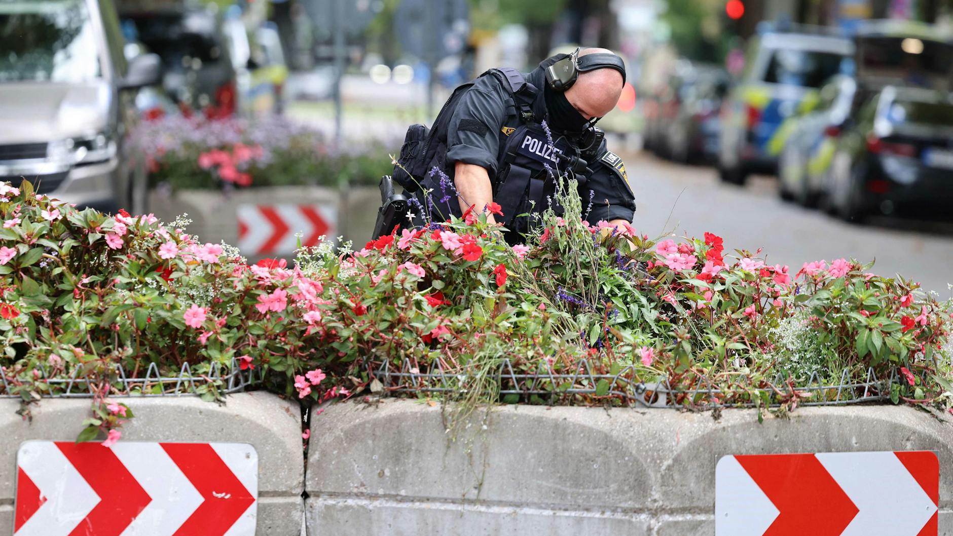 Ein Mitarbeiter der Polizei durchsucht Blumenkästen: Nach einem Brand in München wurde das Gelände der Theresienwiese genauestens unter die Lupe genommen.