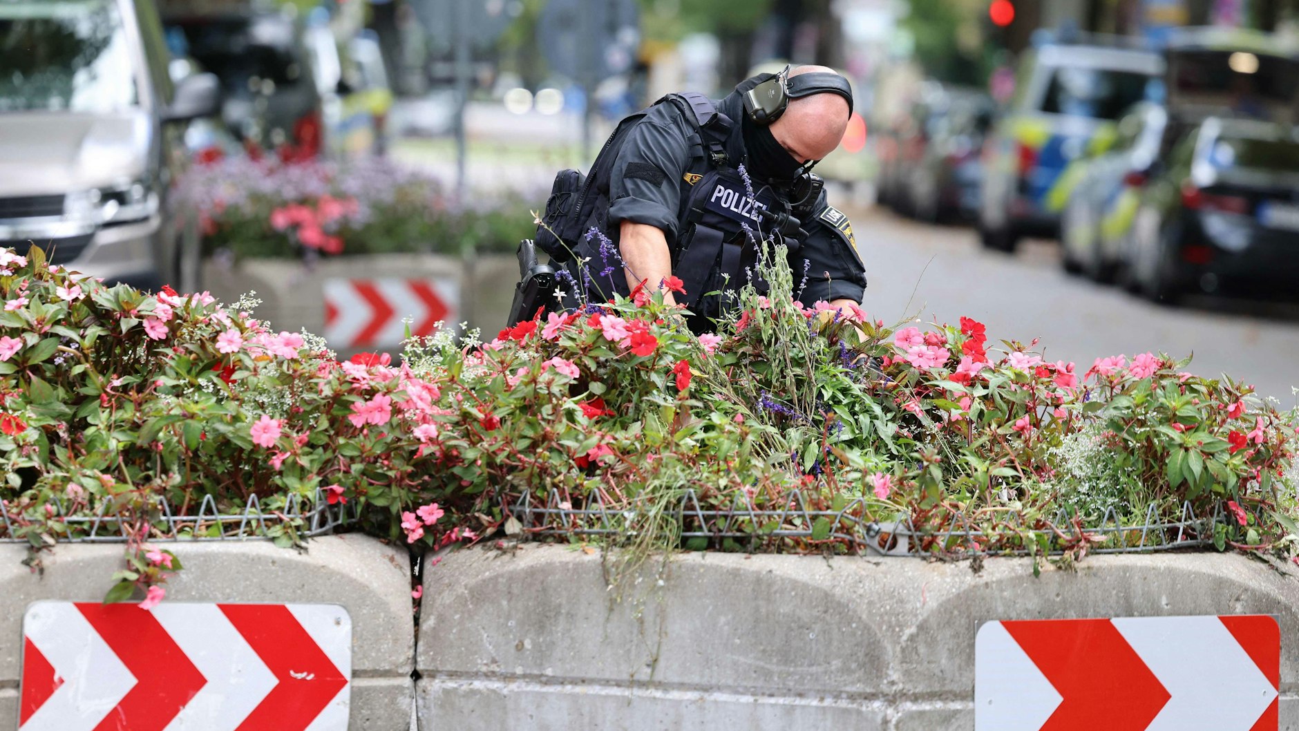 Ein Mitarbeiter der Polizei durchsucht Blumenkästen: Nach einem Brand in München wurde das Gelände der Theresienwiese genauestens unter die Lupe genommen.