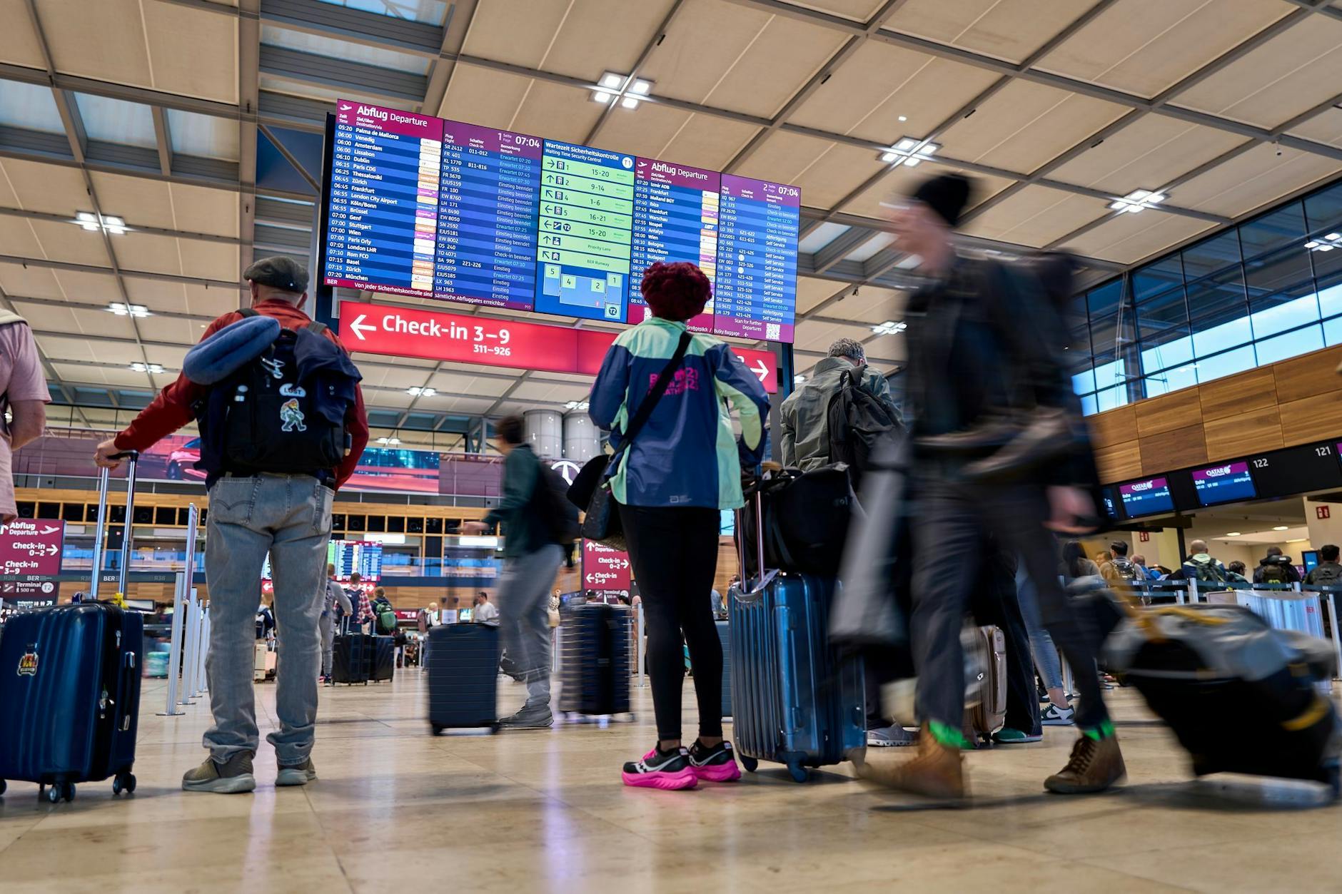 Passagiere vor den Abflugtafeln im Terminal 1 des Flughafens Berlin Brandenburg (BER)