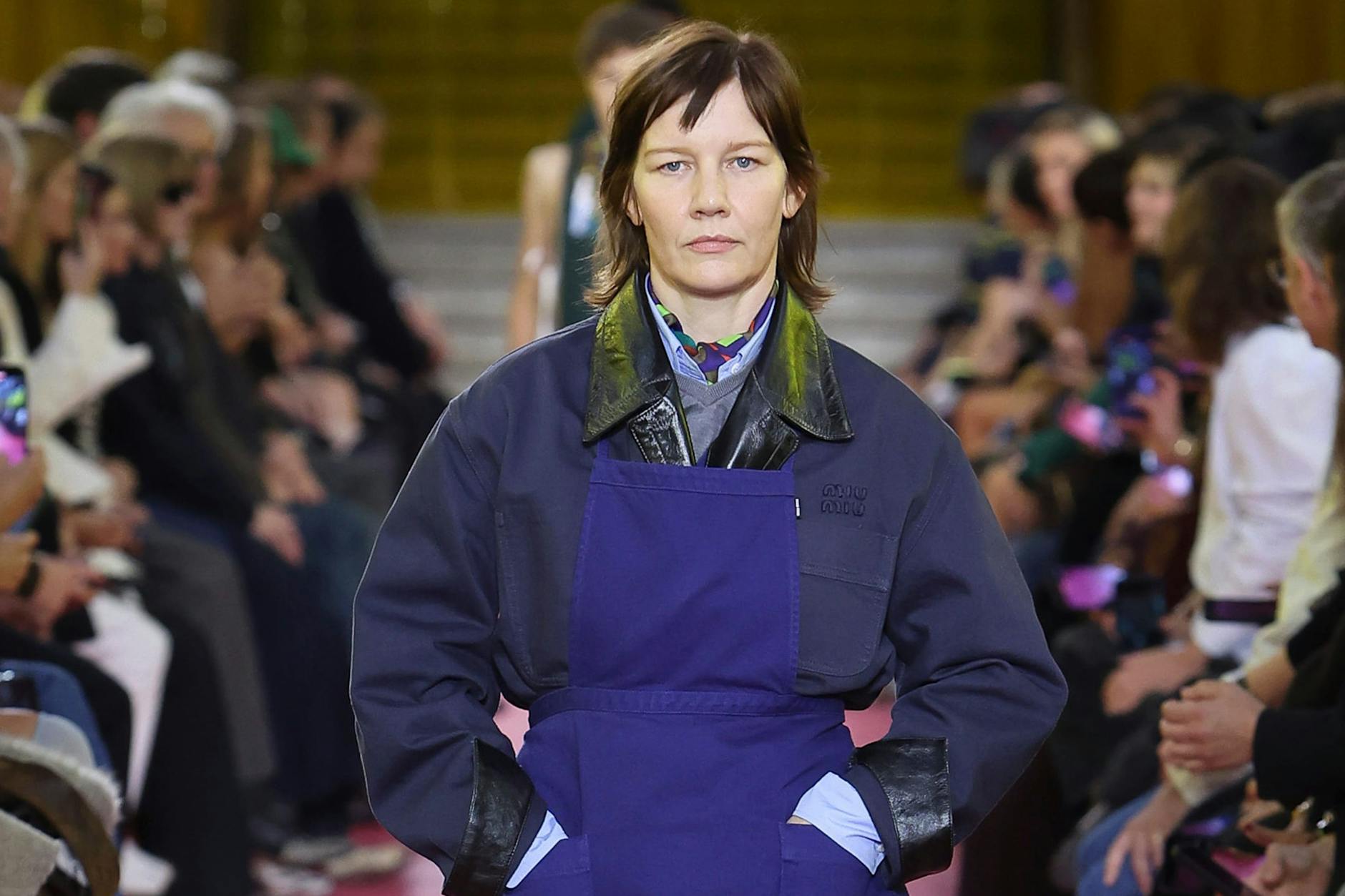 Sandra Hüller mit blauer Schürze auf dem Runway im Palais d’Iéna