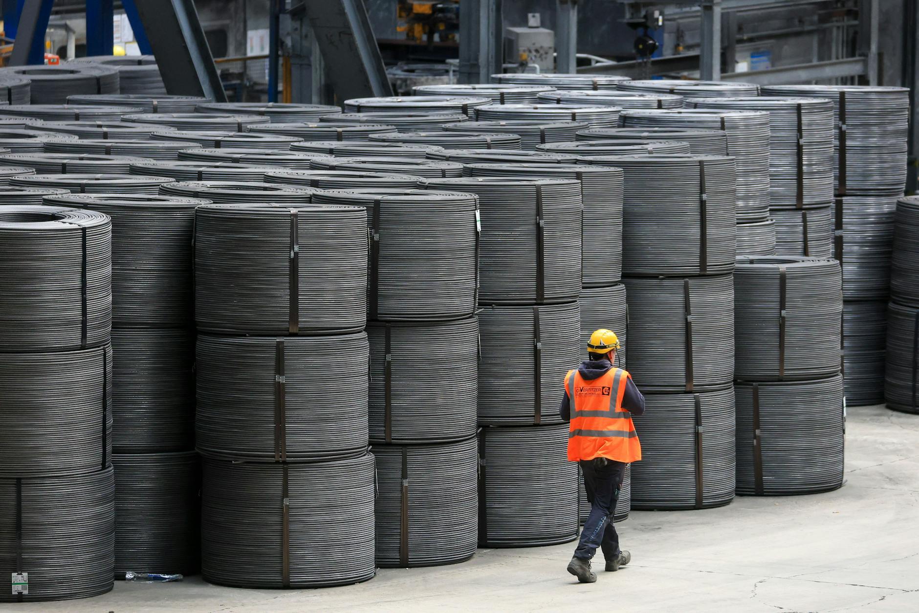 Ein Mitarbeiter geht an Drahtrollen in den Elbe-Stahlwerken Feralpi in Riesa vorbei.