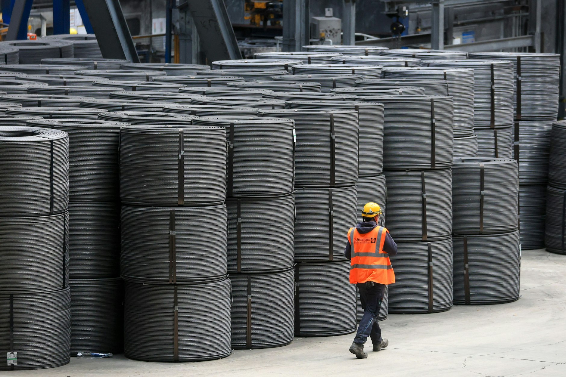 Ein Mitarbeiter geht an Drahtrollen in den Elbe-Stahlwerken Feralpi in Riesa vorbei.