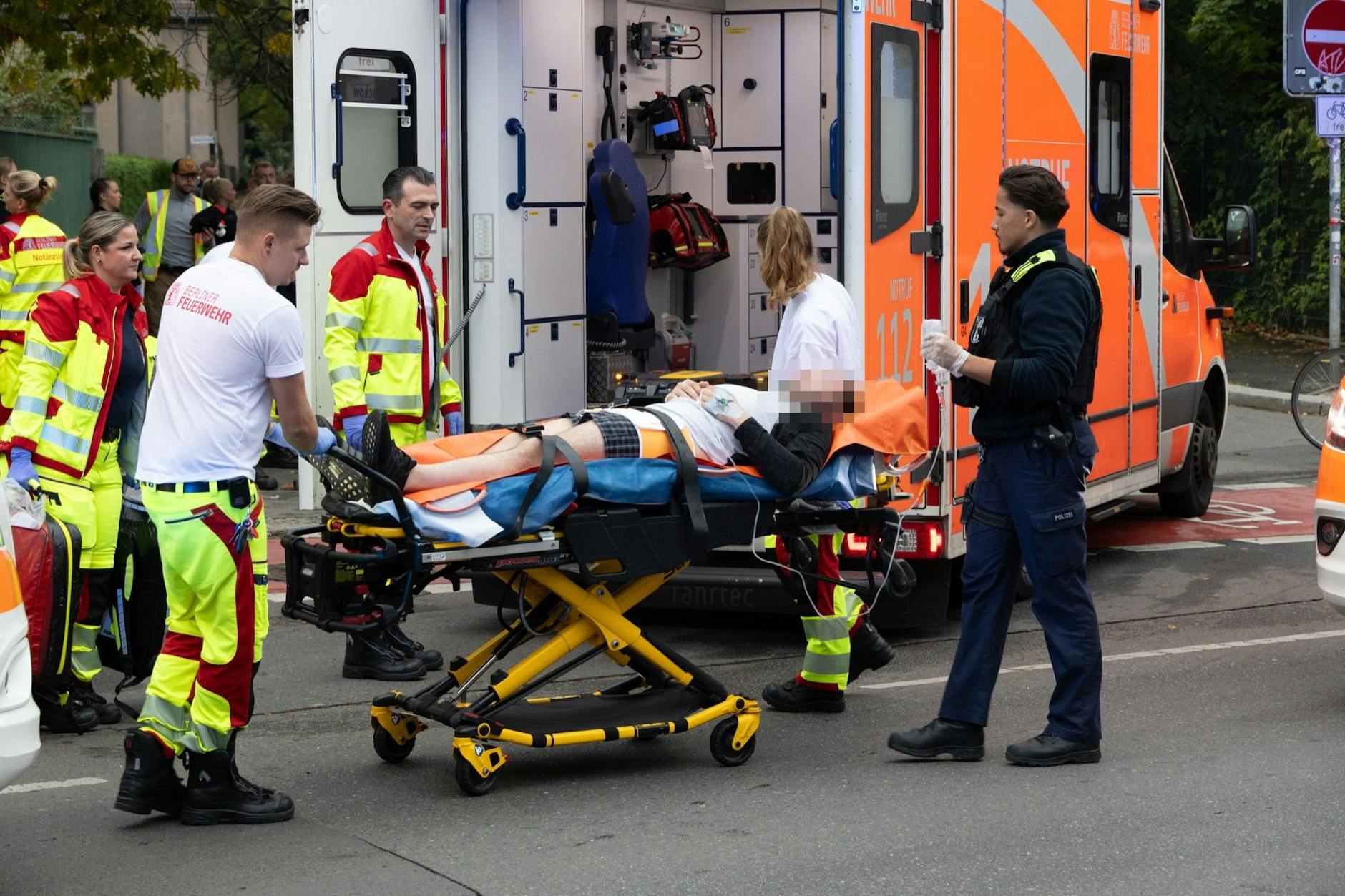 Messer-Angriff in Neukölln: Rettungskräfte versorgen einen der Verletzten, bringen den Mann auf einer Trage in den Krankenwagen.