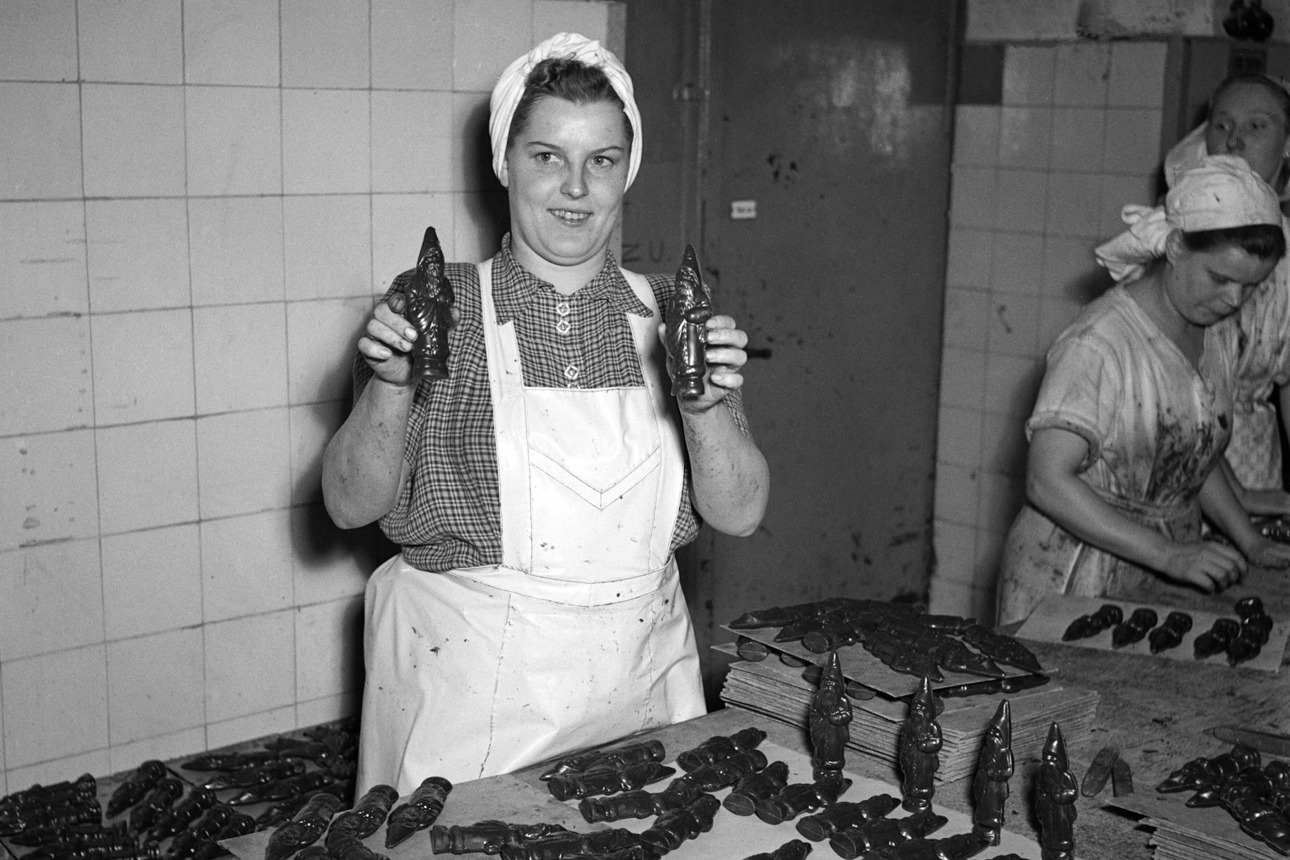 1953 präsentiert eine Mitarbeiterin des VEB Halloren Schokoladenfabrik in Halle Schokoladenweihnachtsmänner.