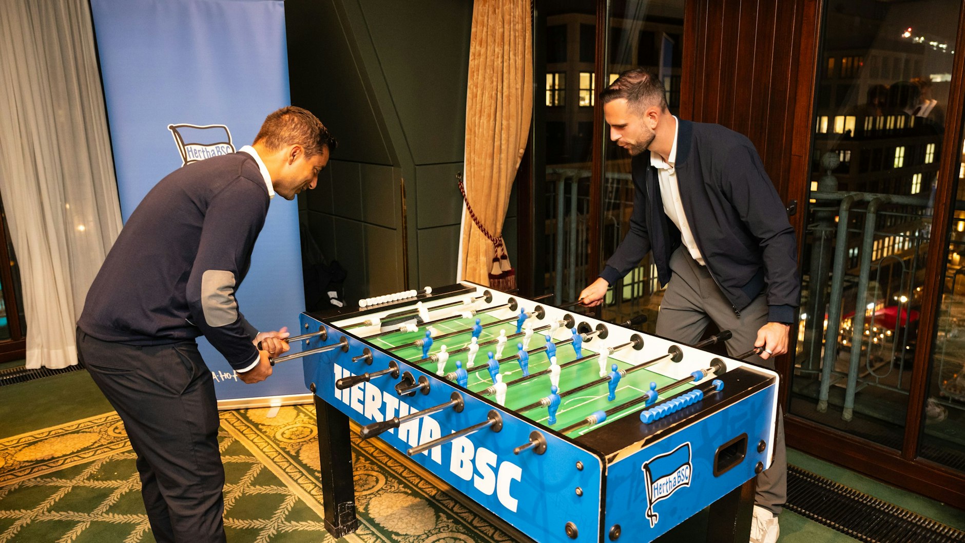Sami Allagui (l.), Sportkoordinator von Hertha BSC, und Torwart Marius Gersbeck spielen sich am Tischkicker für die Duelle mit den Gästen im Berlin Capital Club warm.